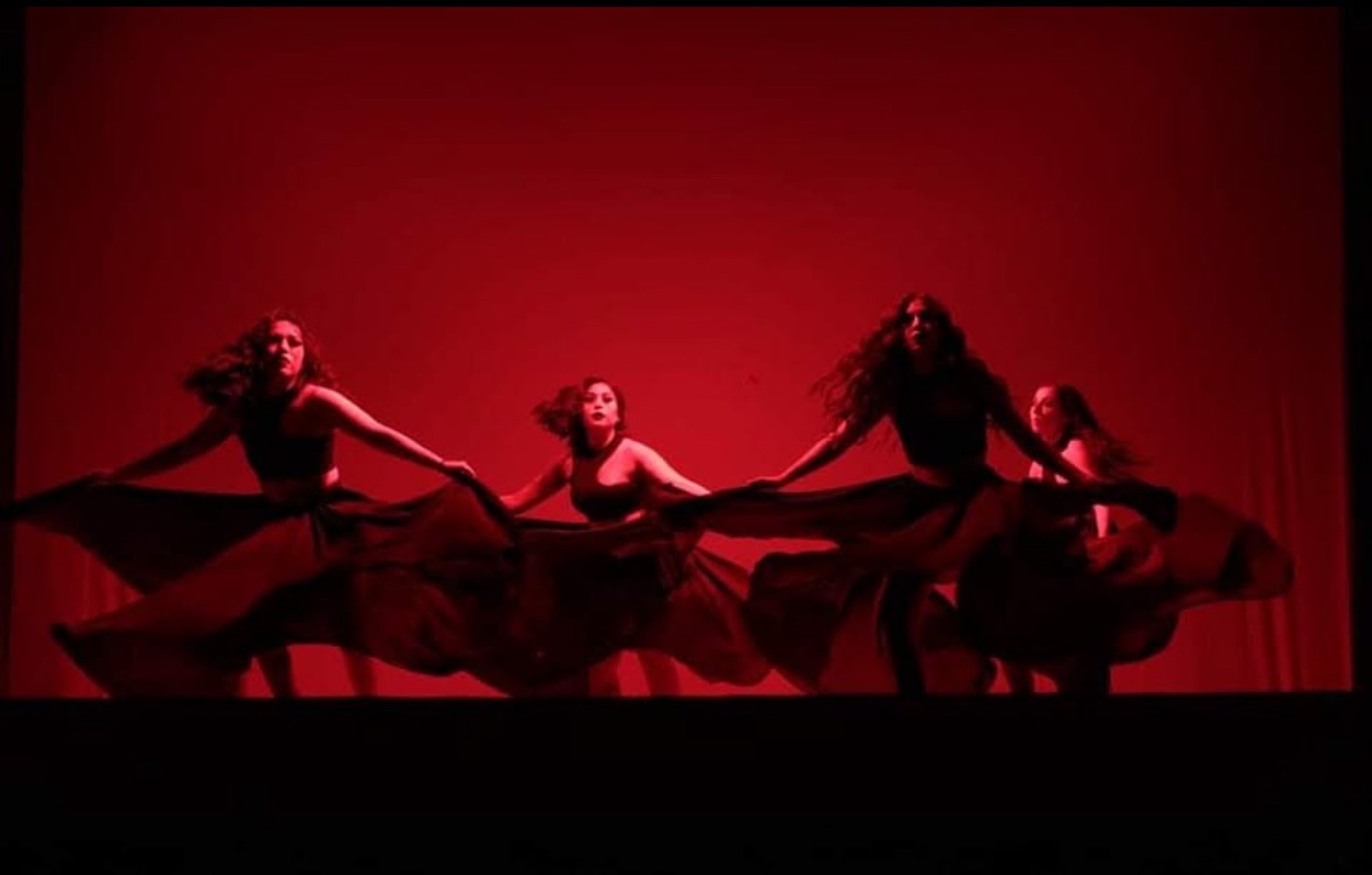 Bailarinas de danza etnocontemporánea de colectiva roja en esecnario con luces rojas