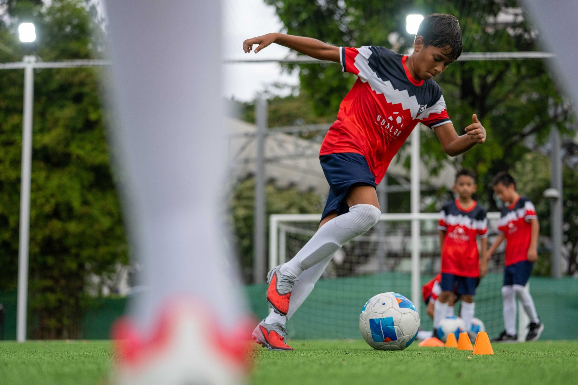 Young man kicking soccer ball on field