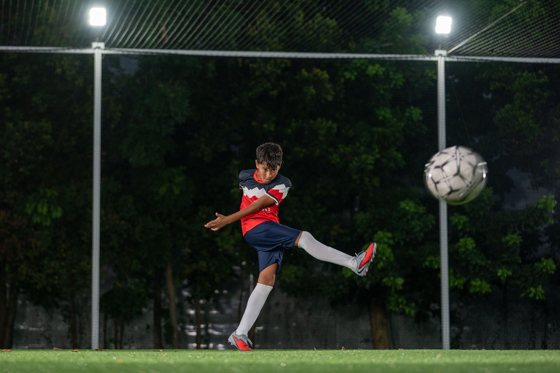 Young man kicking soccer ball on field