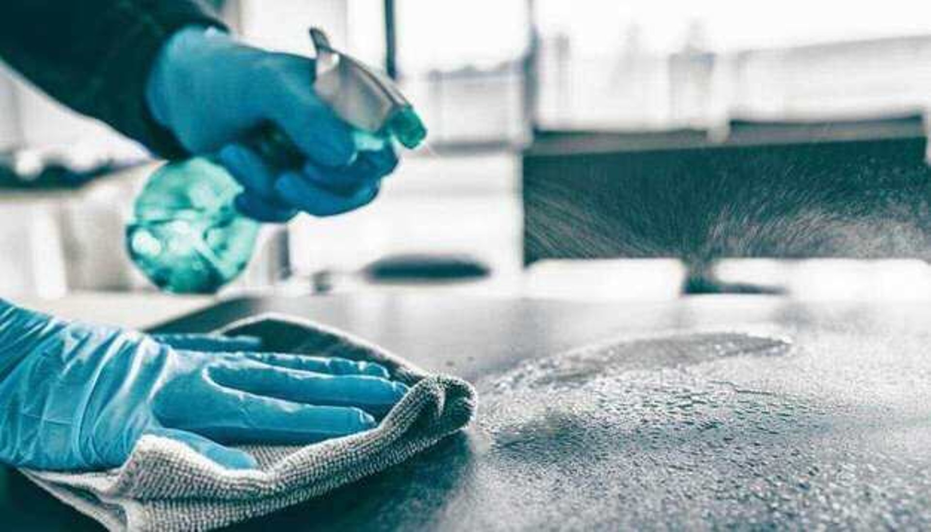 A person in yellow gloves and blue gloves cleaning a floor