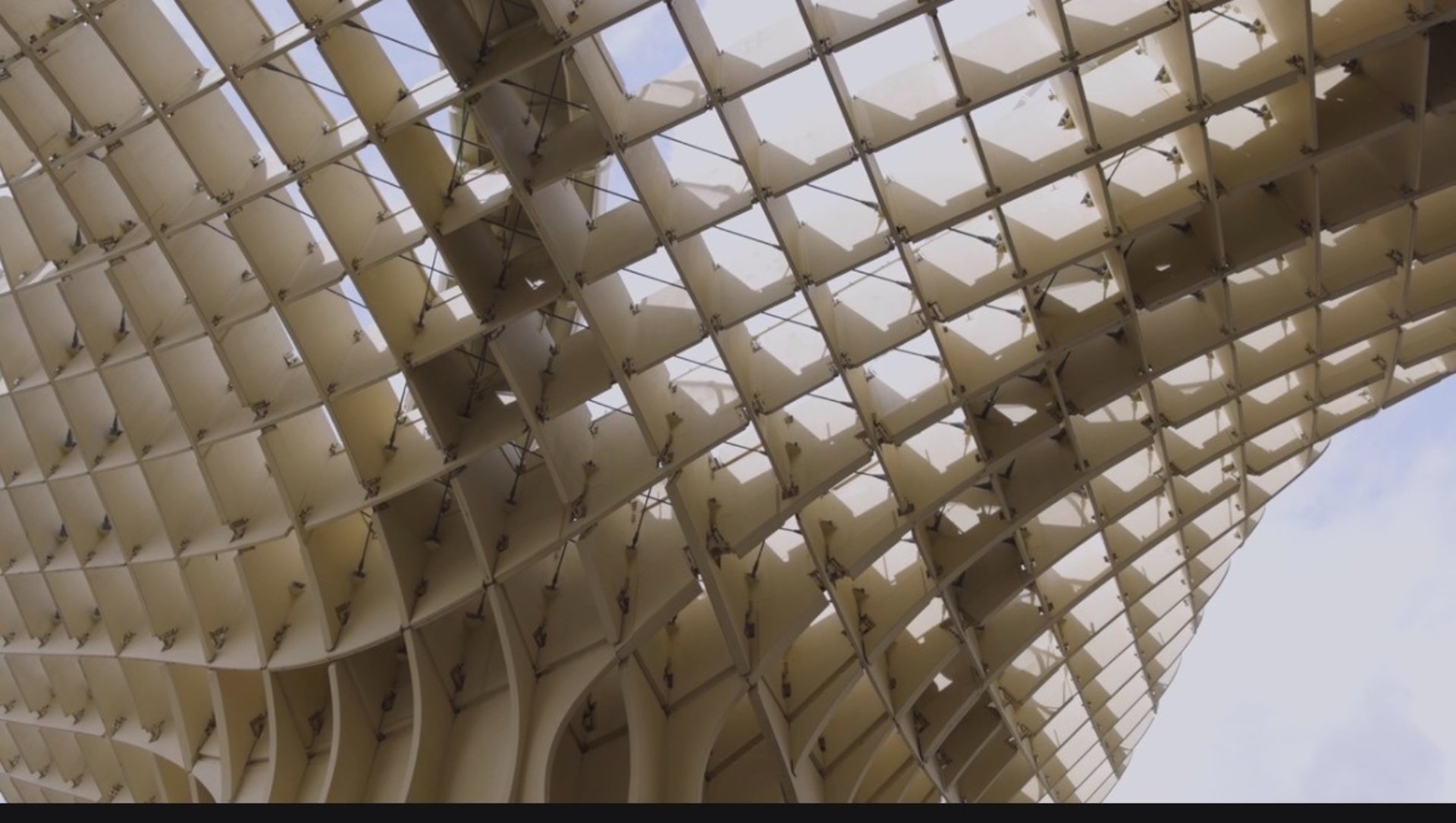 an abstract photo of a curved building with a blue sky in the background