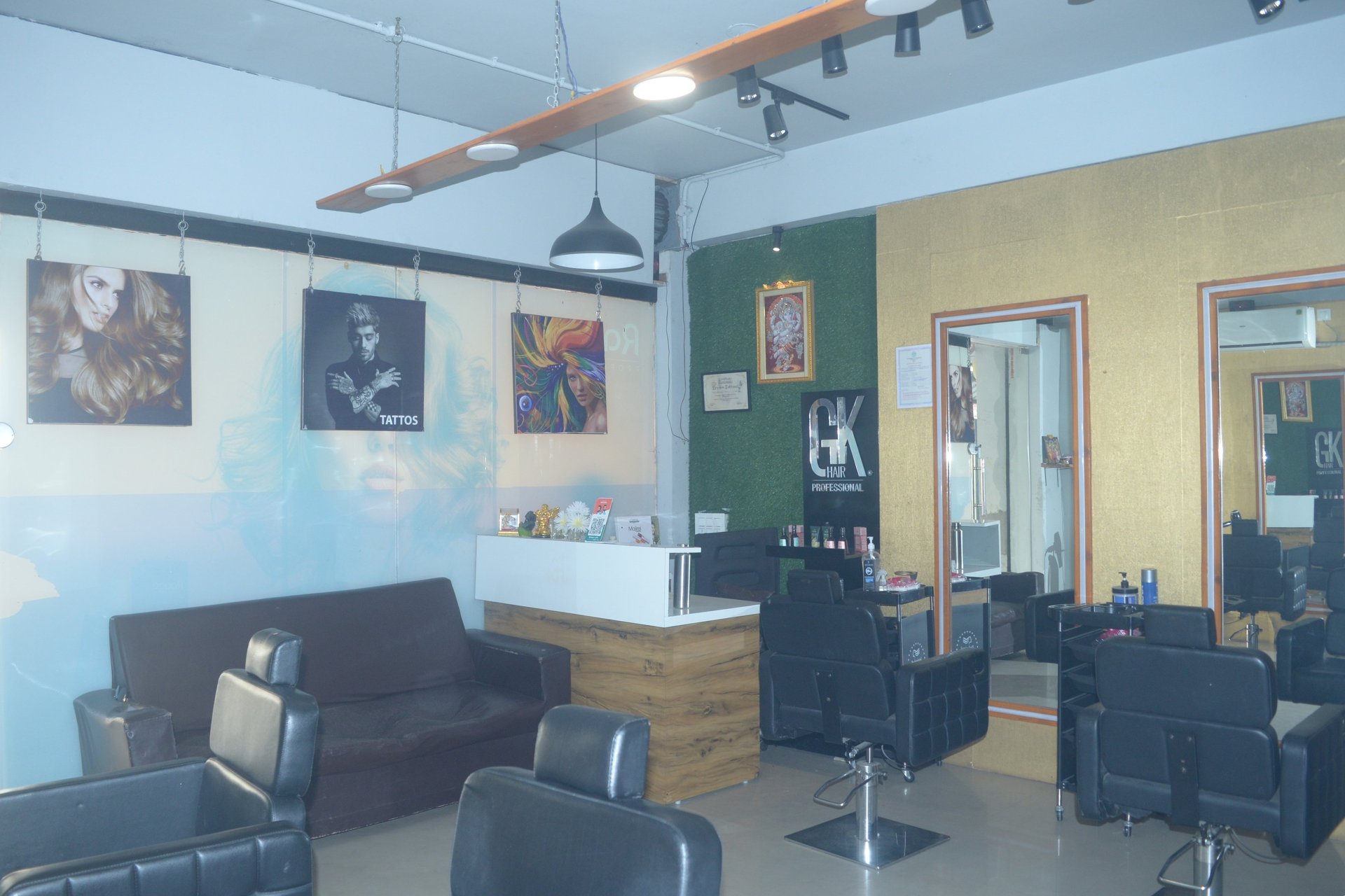 grayscale photo of woman using laptop near three salon chairs