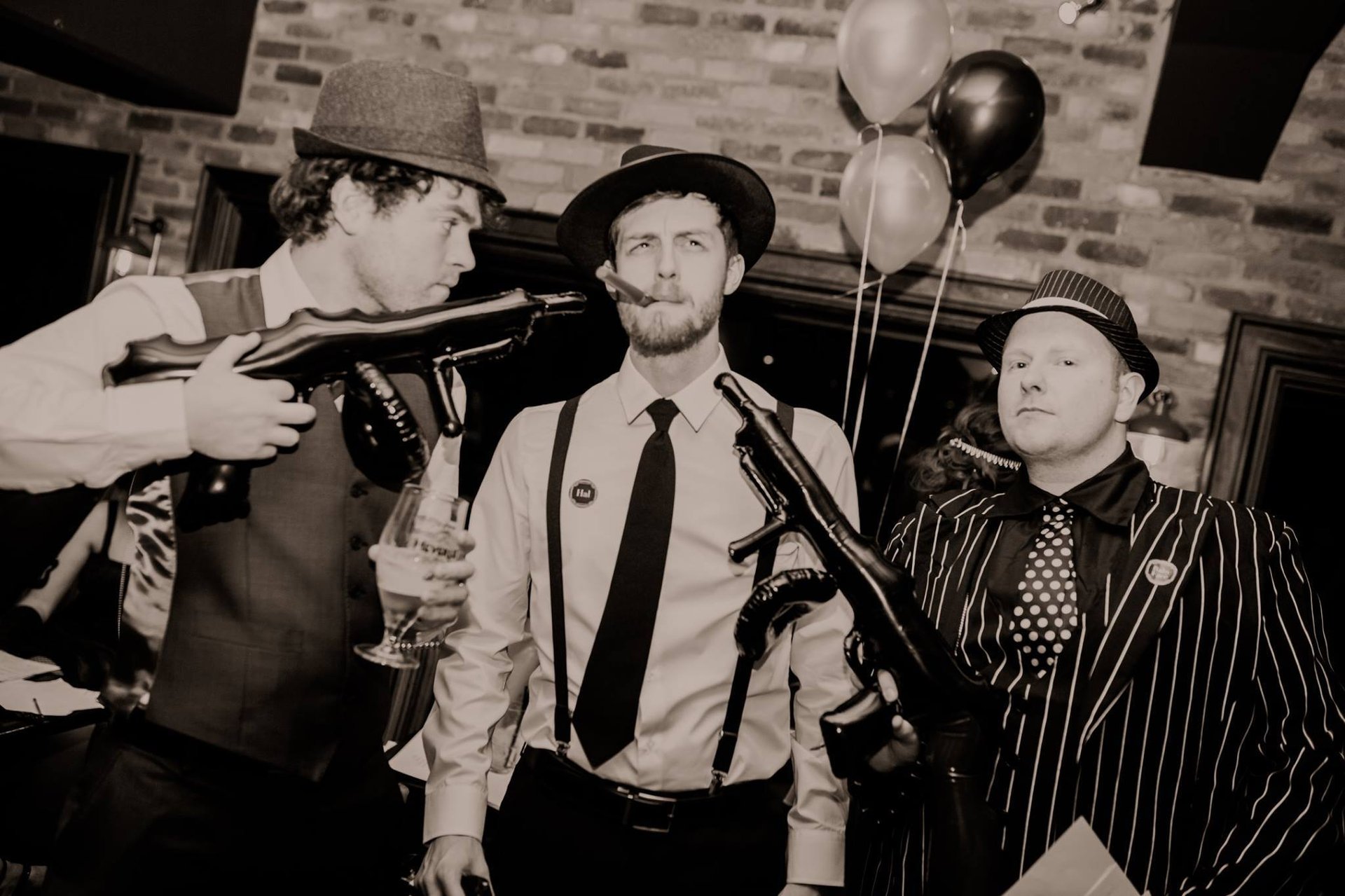 Three men dressed as gangsters at a themed murder mystery party.