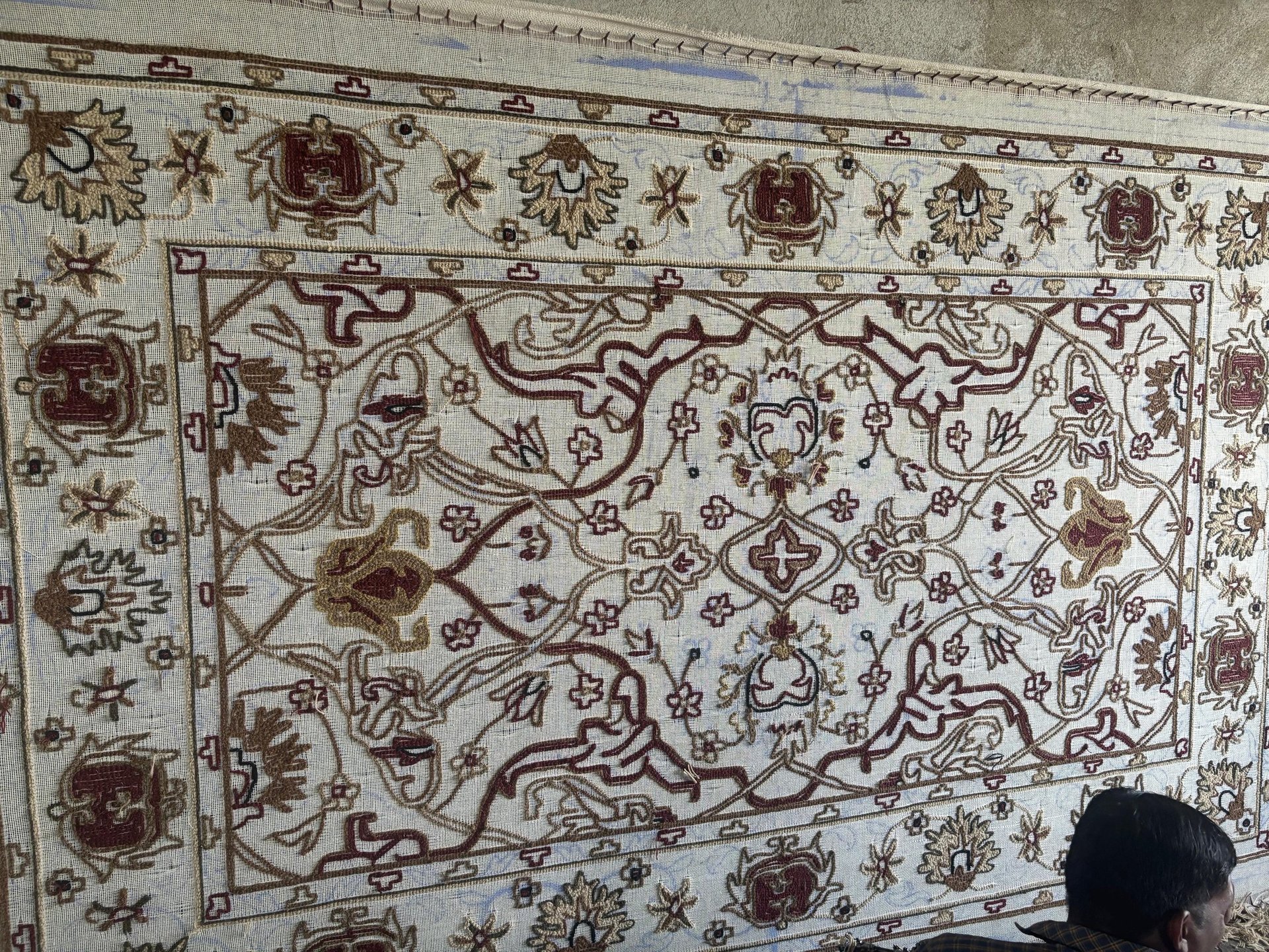 A man sitting on a bed surrounded by rugs