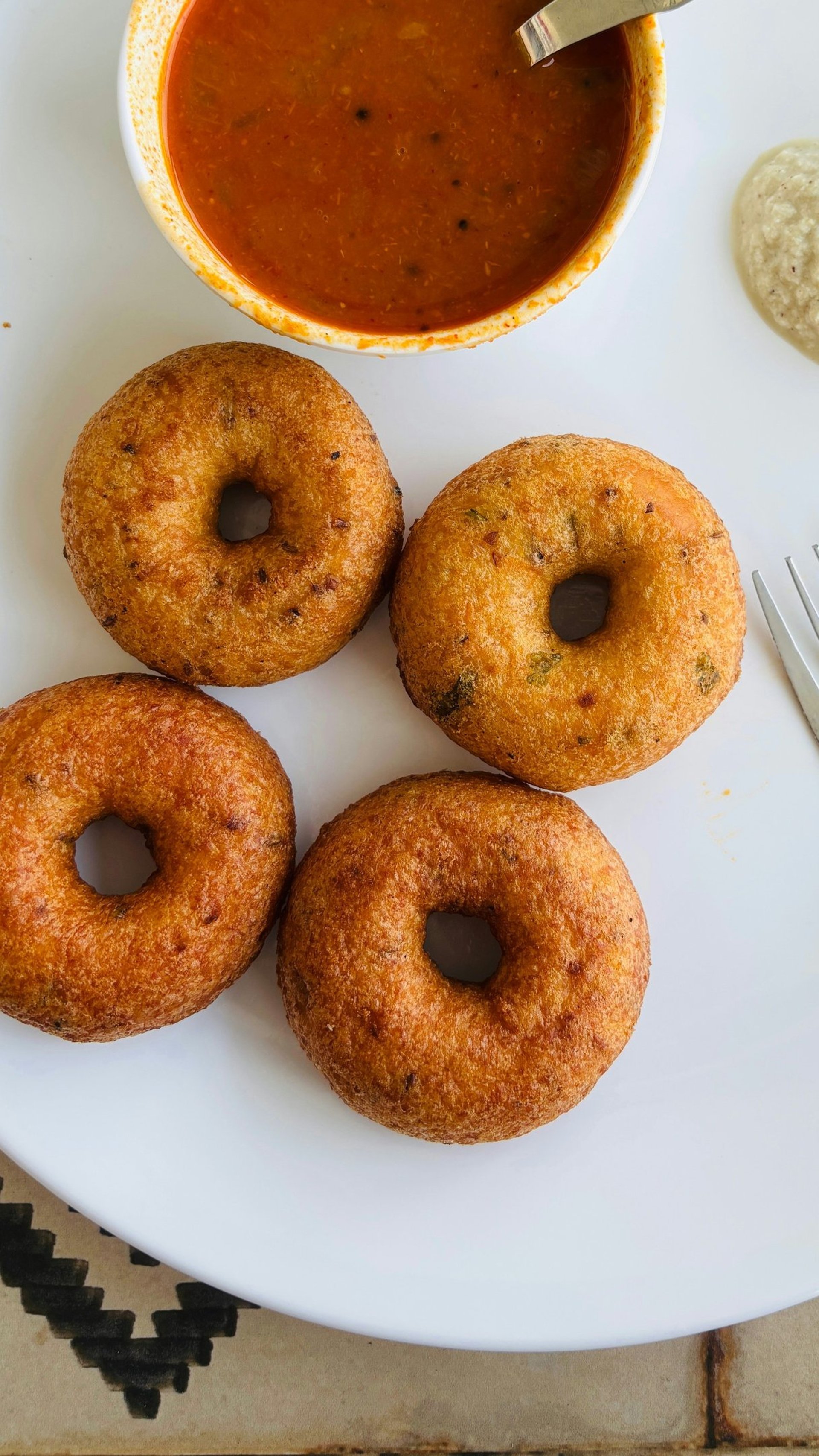 A white plate topped with donuts next to a bowl of sauce