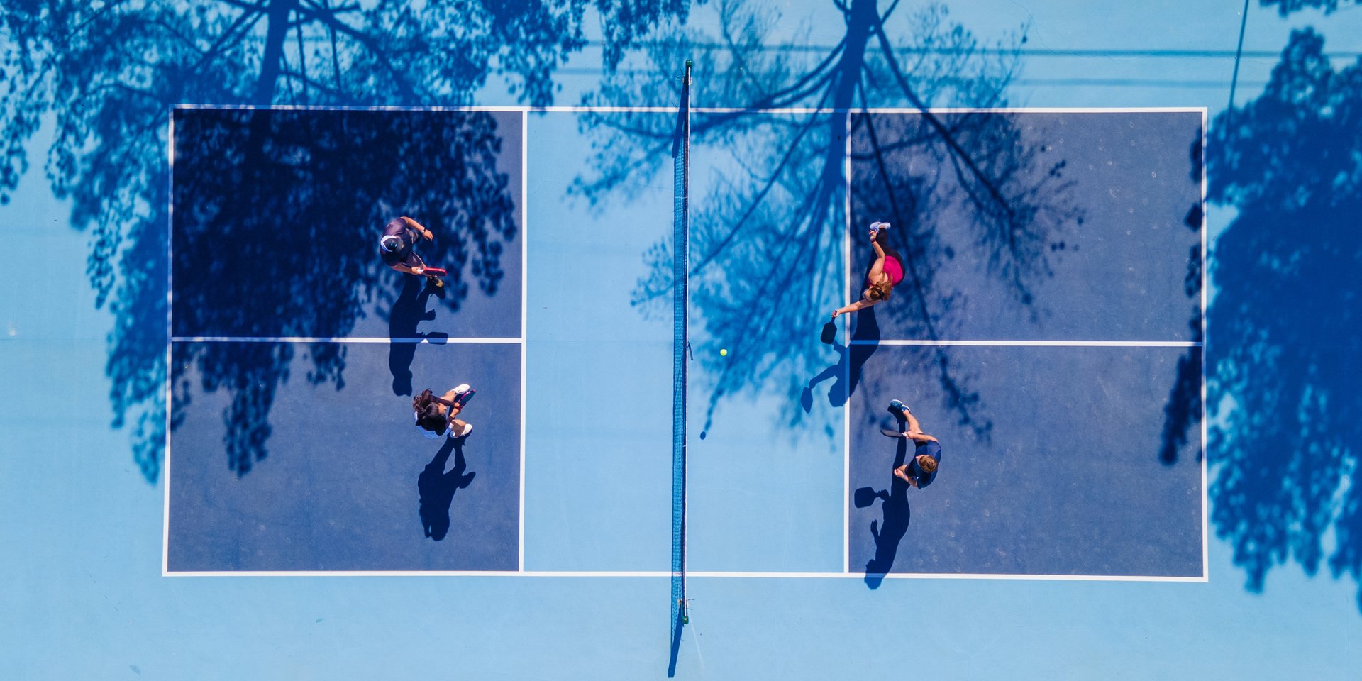 Players compete in a pickleball match on a blue court.