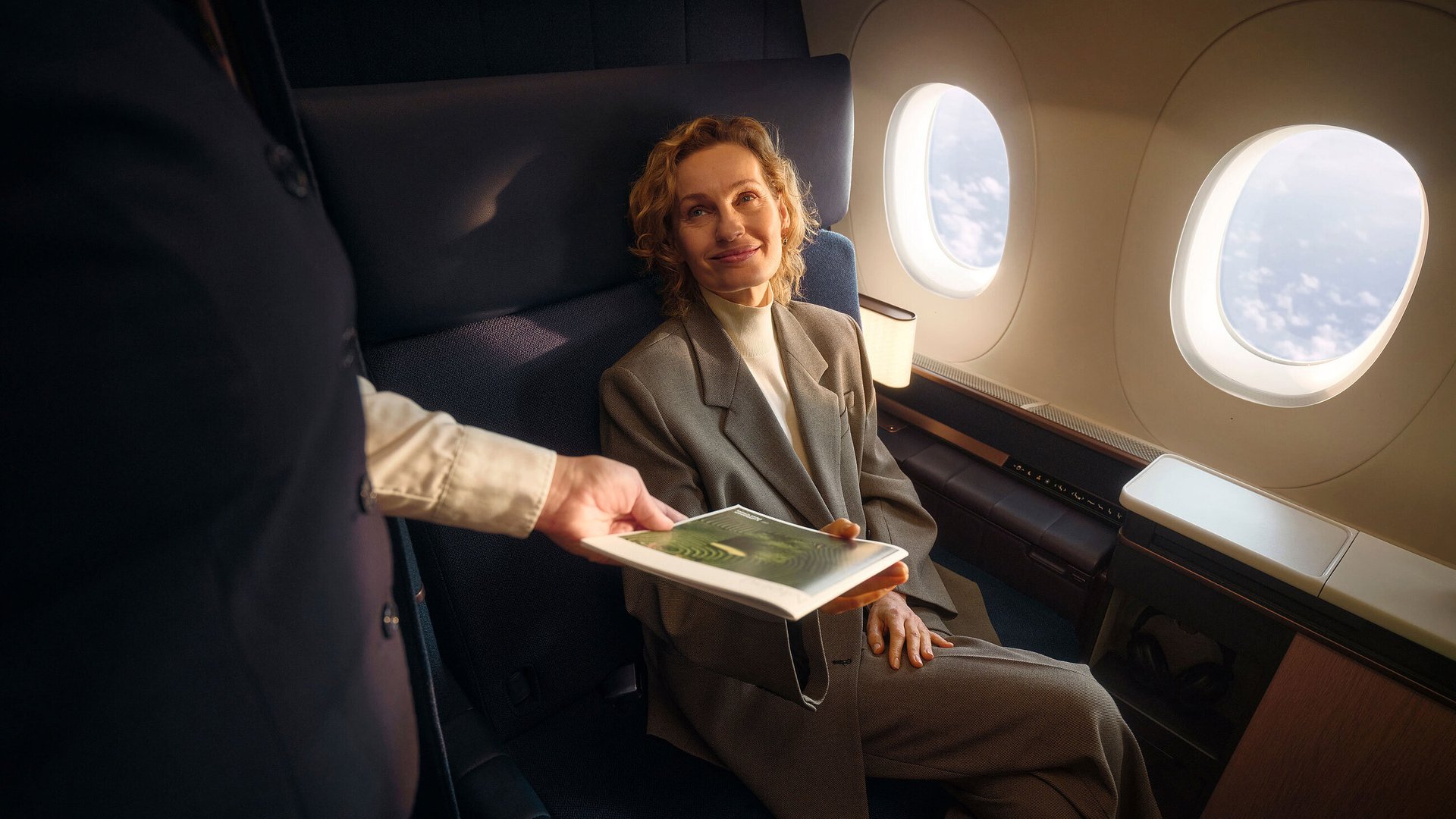 man sitting on gang chair with feet on luggage looking at airplane
