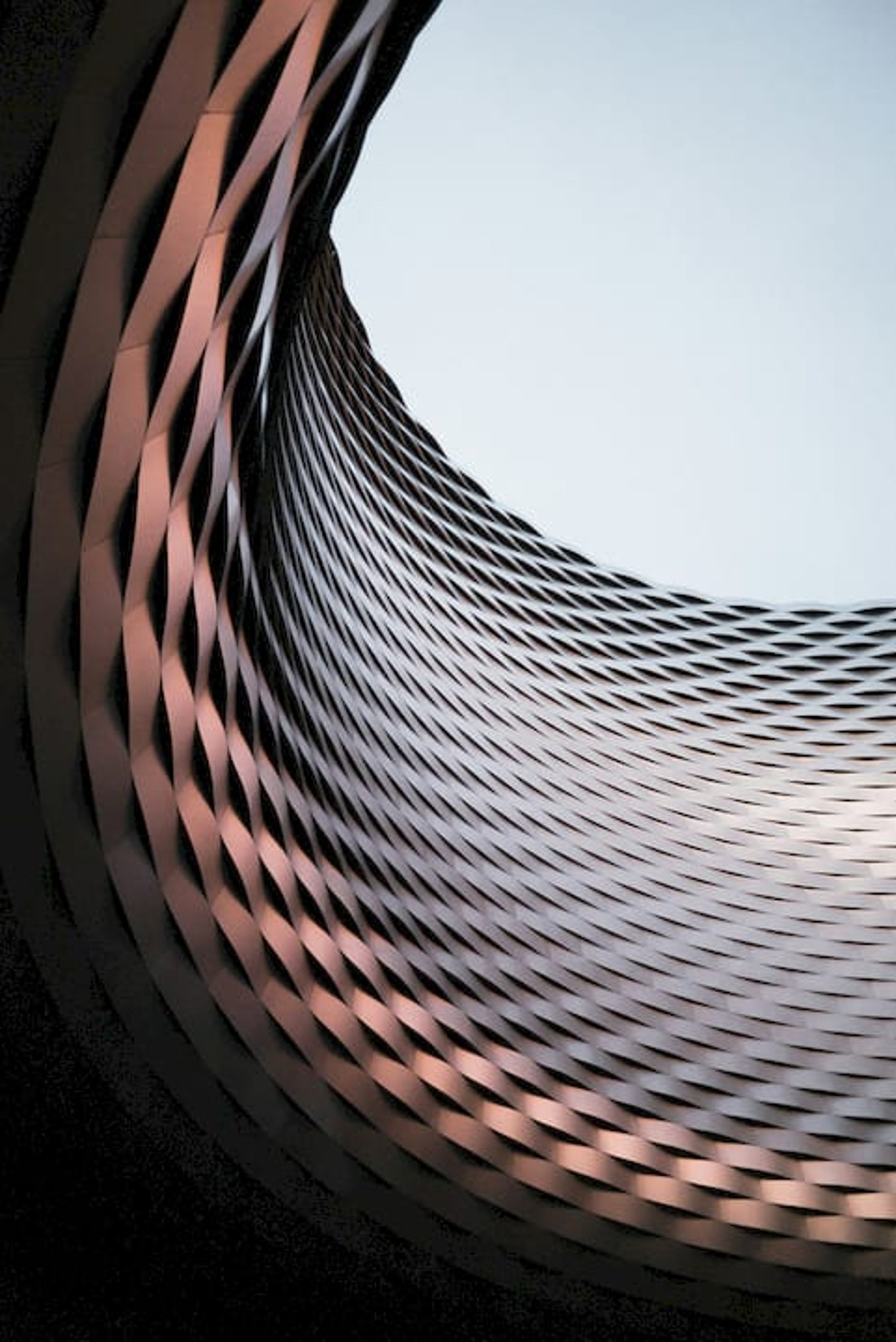 an abstract photo of a curved building with a blue sky in the background