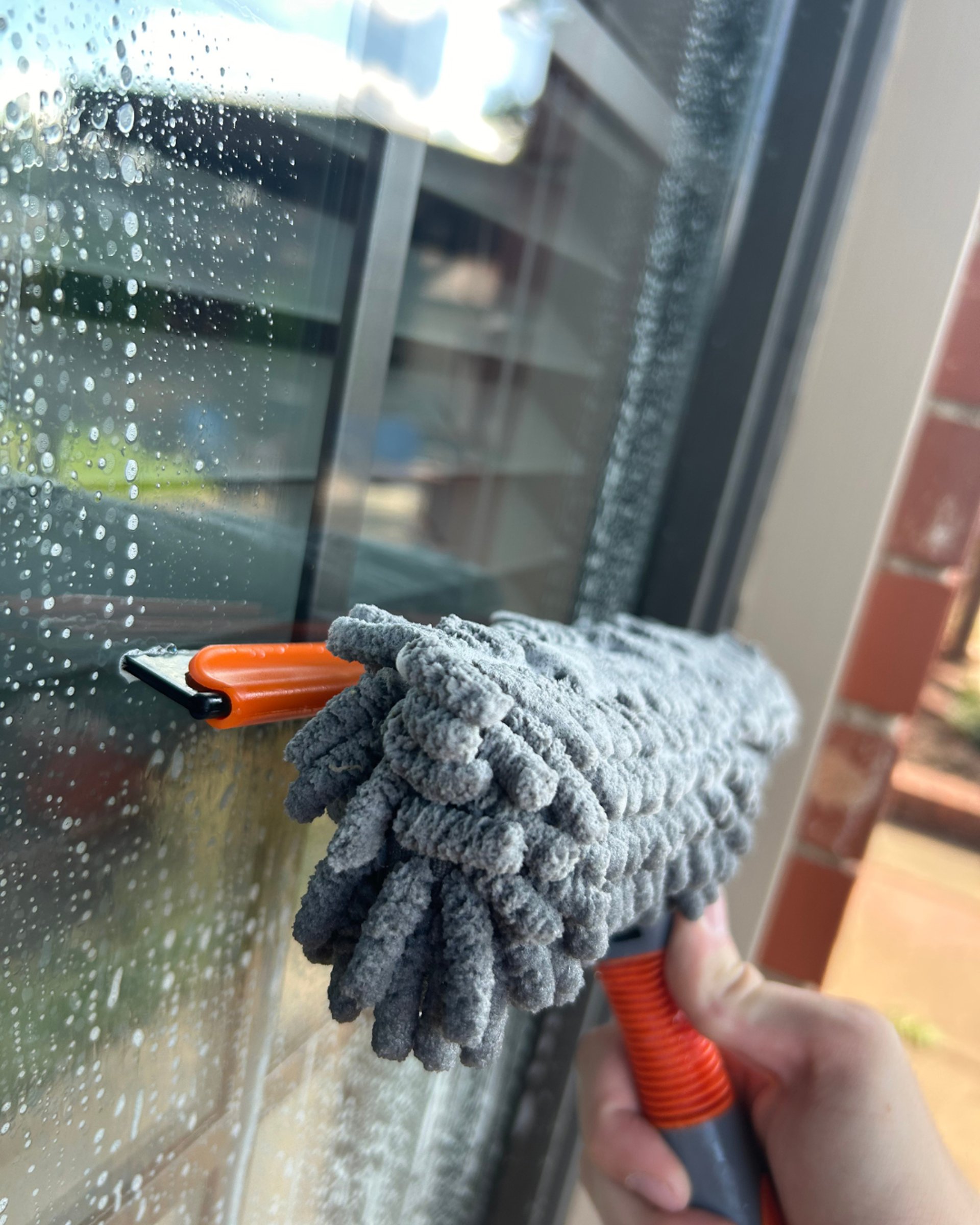 Man cleaning a storefront window with a squeegee.