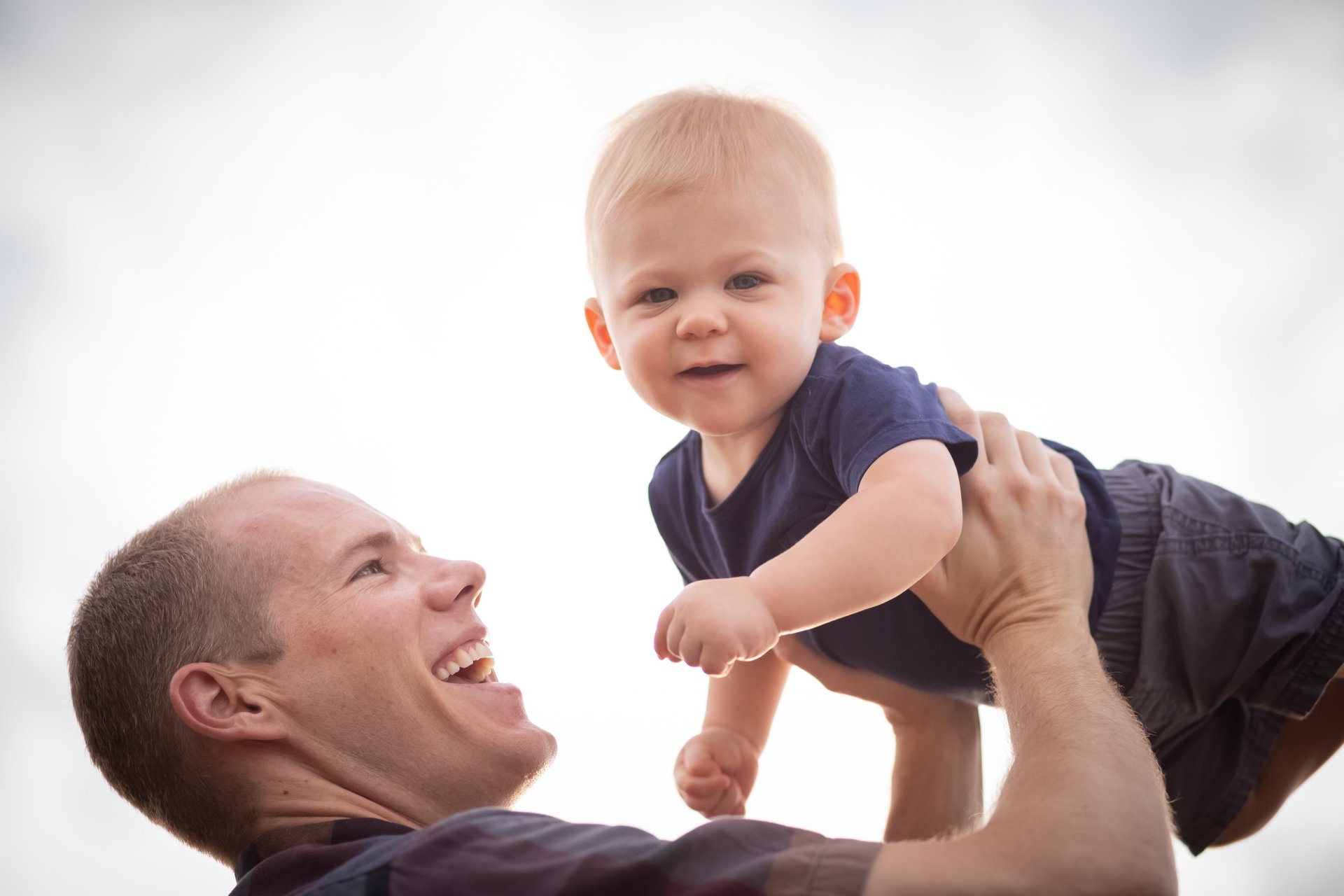 Father holding son up in air smiling in outdoor family photography session in Phoenix, Arizona
