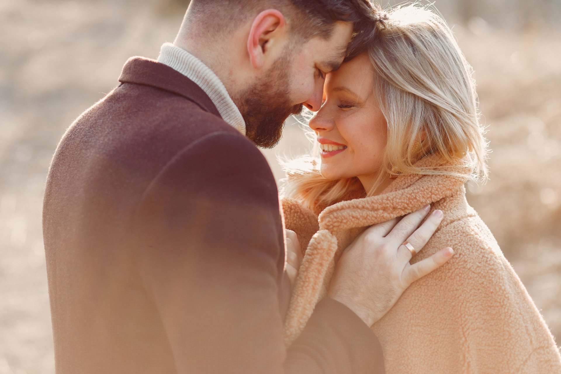 man and woman facing beside each other standing on rocky shore during day