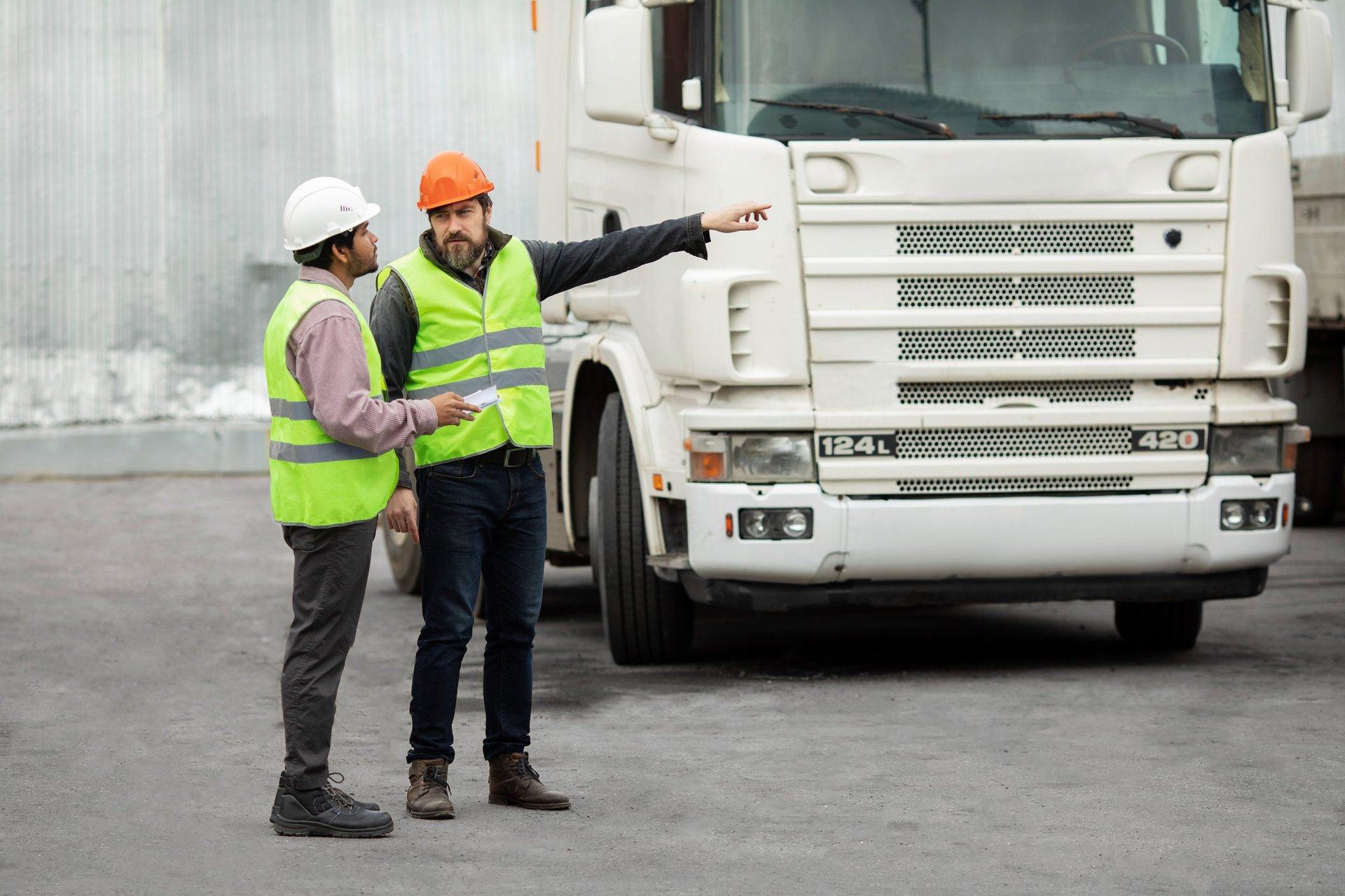 a couple of men standing on the back of a green truck