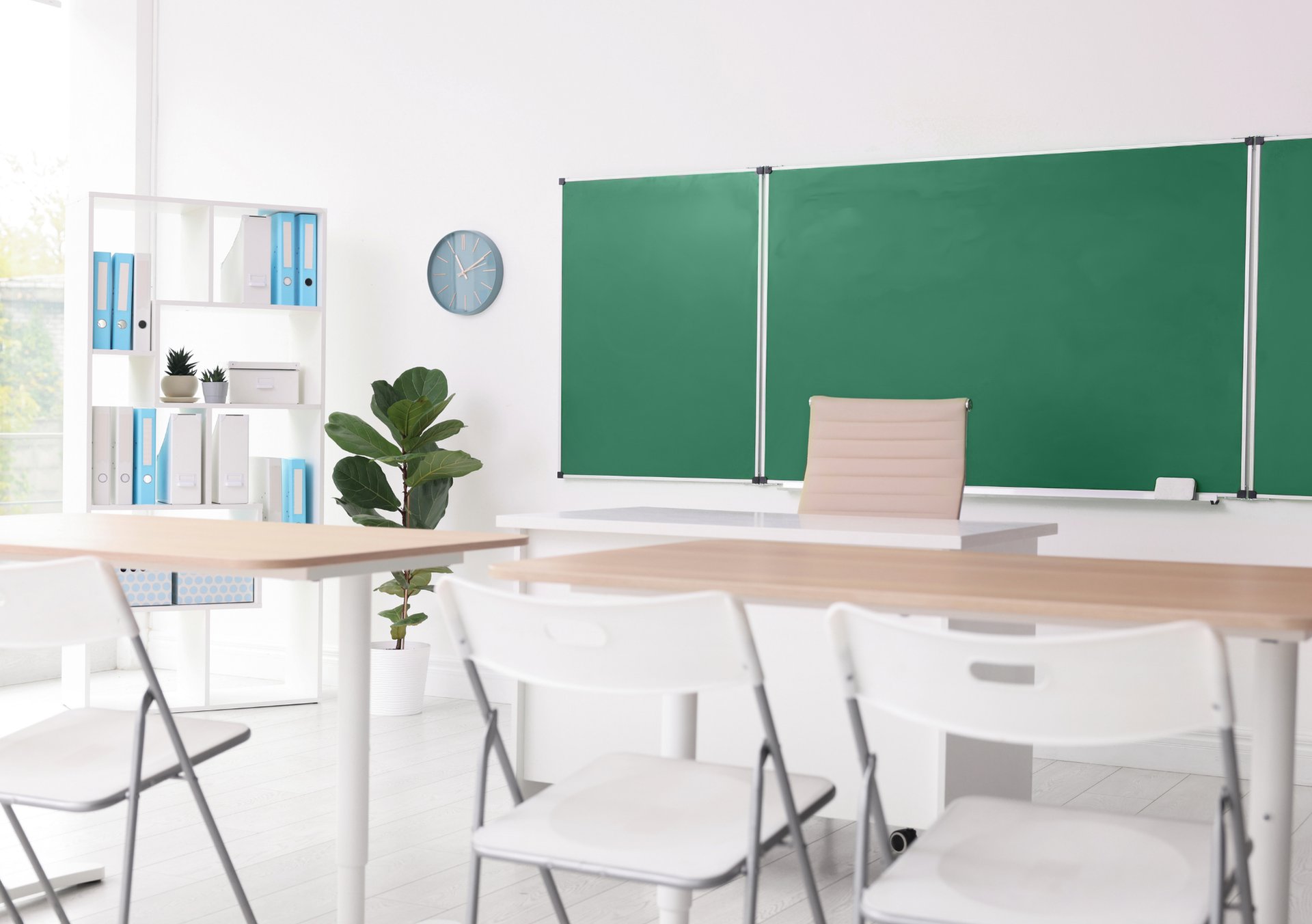 grayscale photography of teacher standing near chalkboard and children sitting on chairs