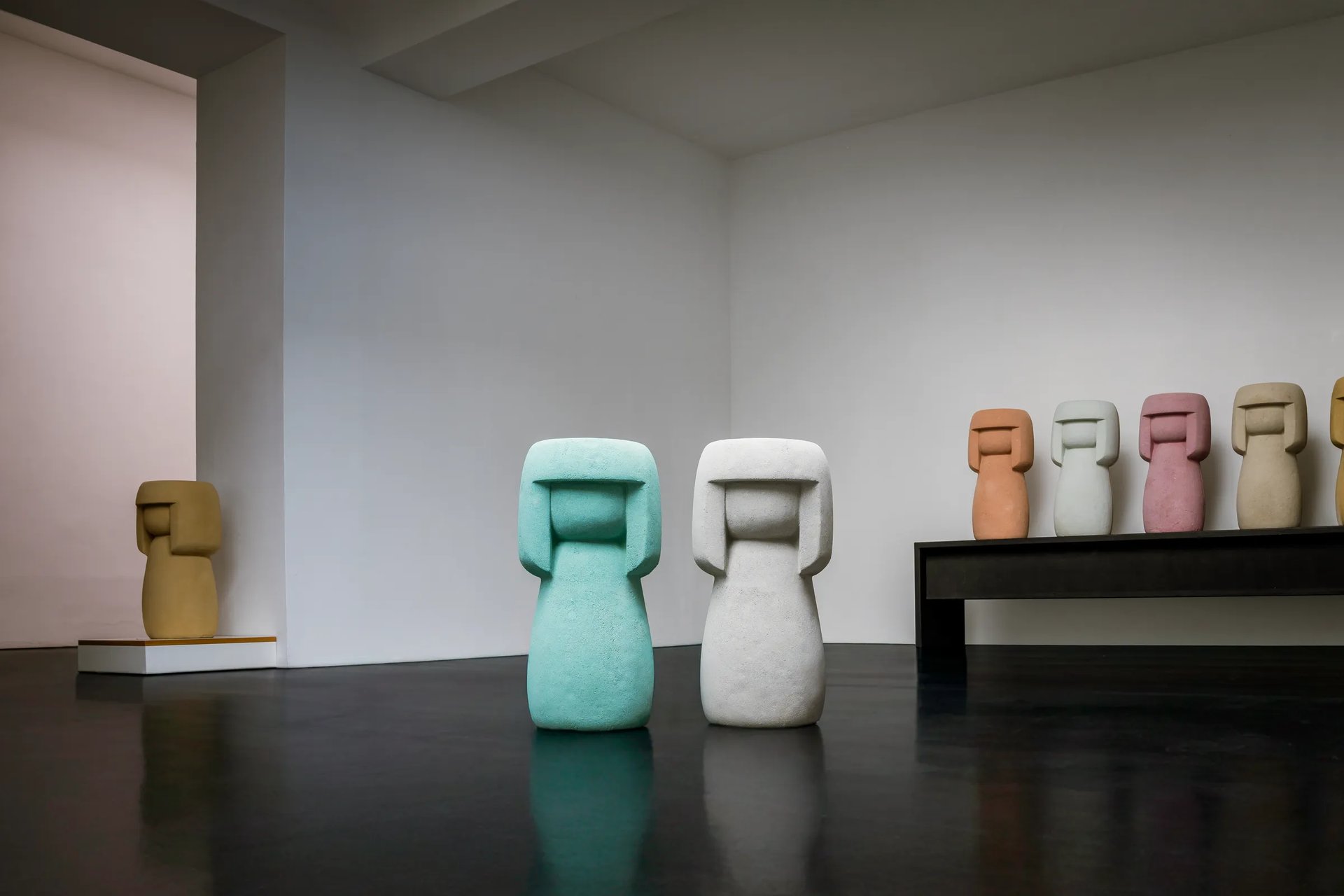 8 handgefertigte Kokeshis aus Stein: Unikate auf einer Bank und freistehend. Exklusive Skulpturen gemacht in Handarbeit