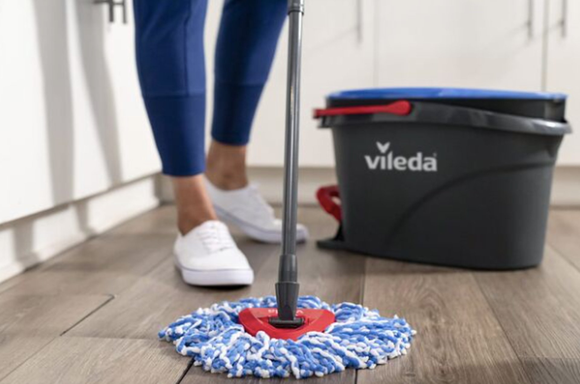 person holding blue textile near clear glass bottle