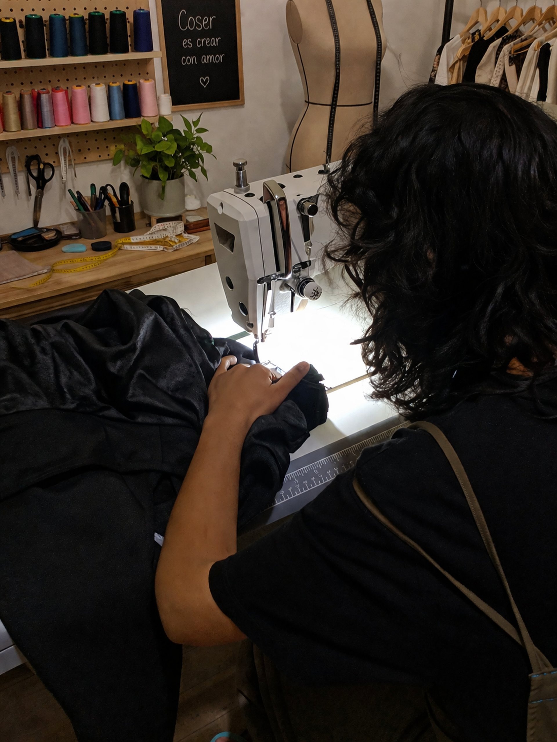 Mujer cosiendo a máquina en taller de costura de la tienda viento luminiscente de ropa artesanal boho, bohemio hippie