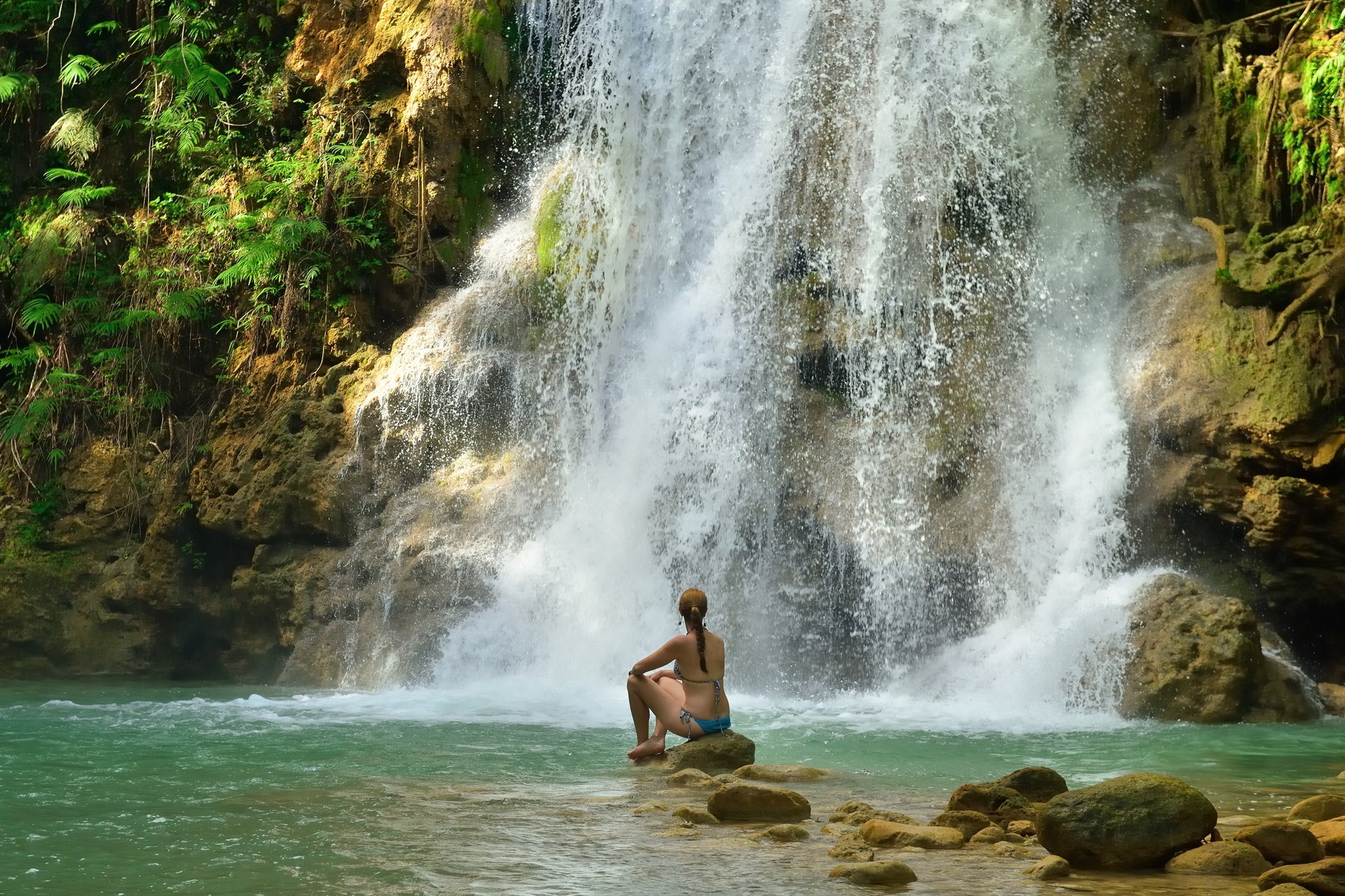 Woman relaxing at El Limón Waterfall surrounded by lush jungle in the Dominican Republic