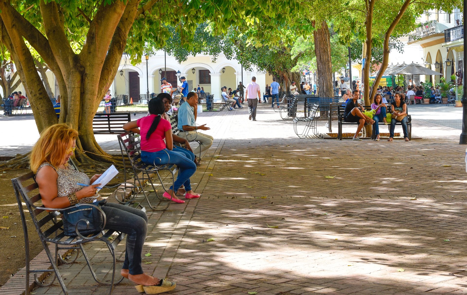 People relaxing in a shaded plaza in Santo Domingo Dominican Republic enjoying local culture and daily life