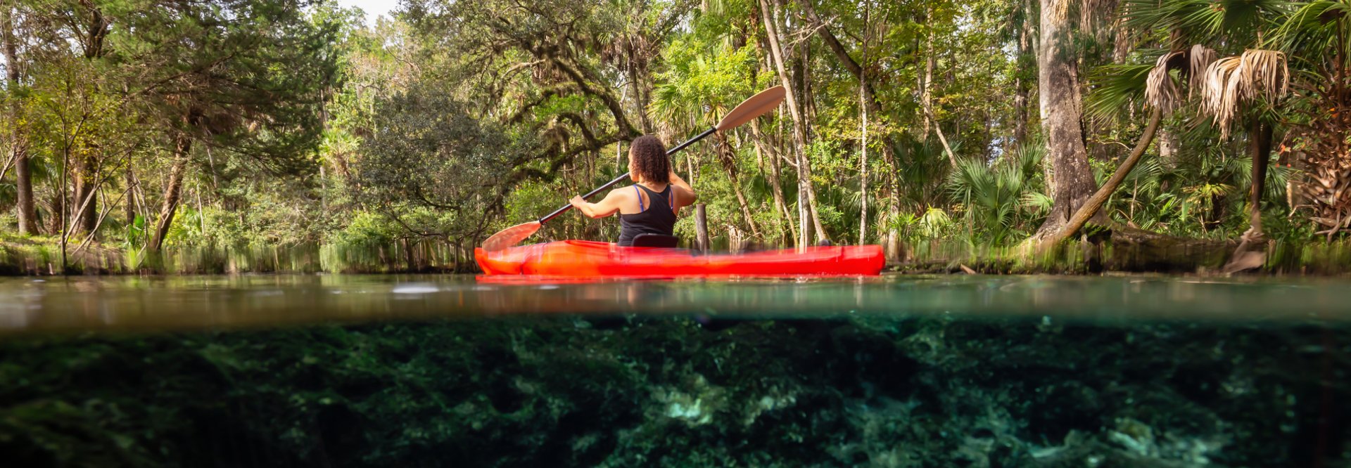 A girl kayaking in a lake near an underwater cave formation in Central Florida