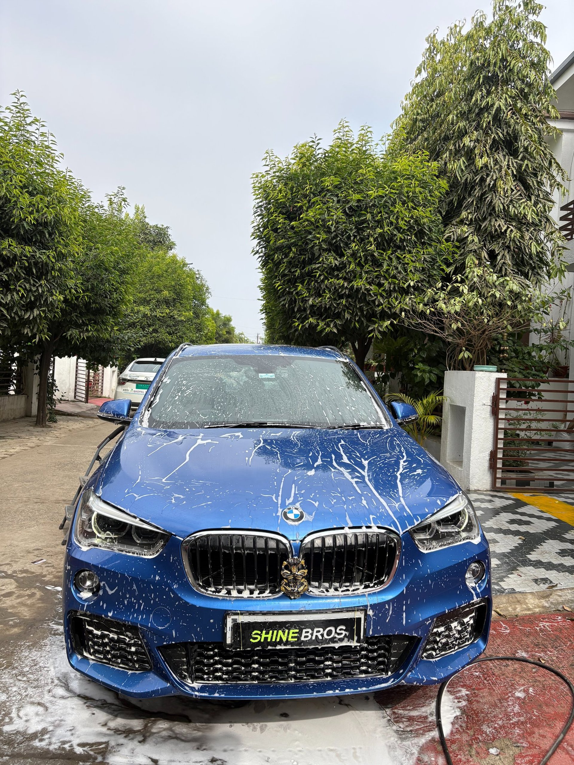A blue car is covered in soap suds.
