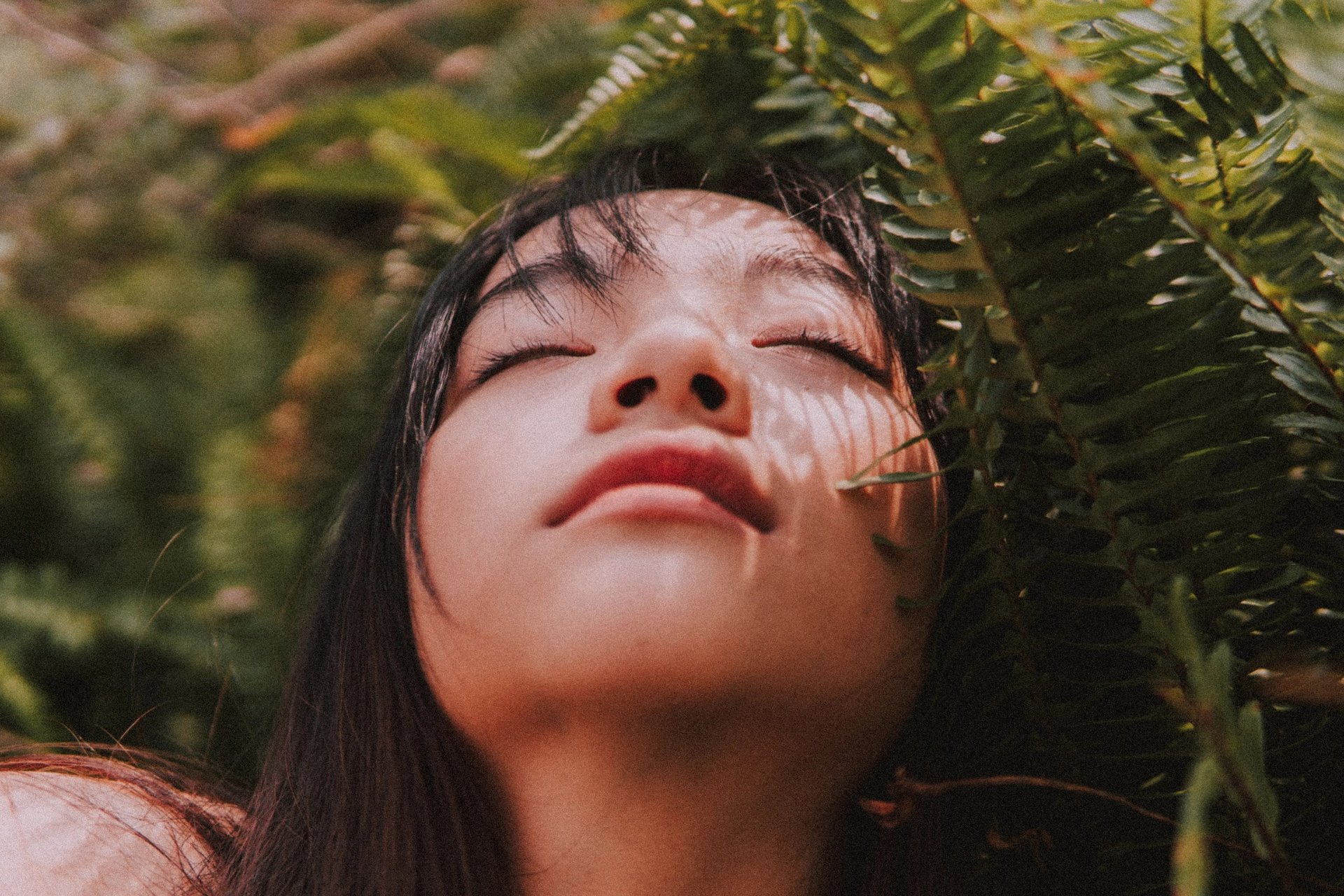 serene woman with eyes closed among fernss