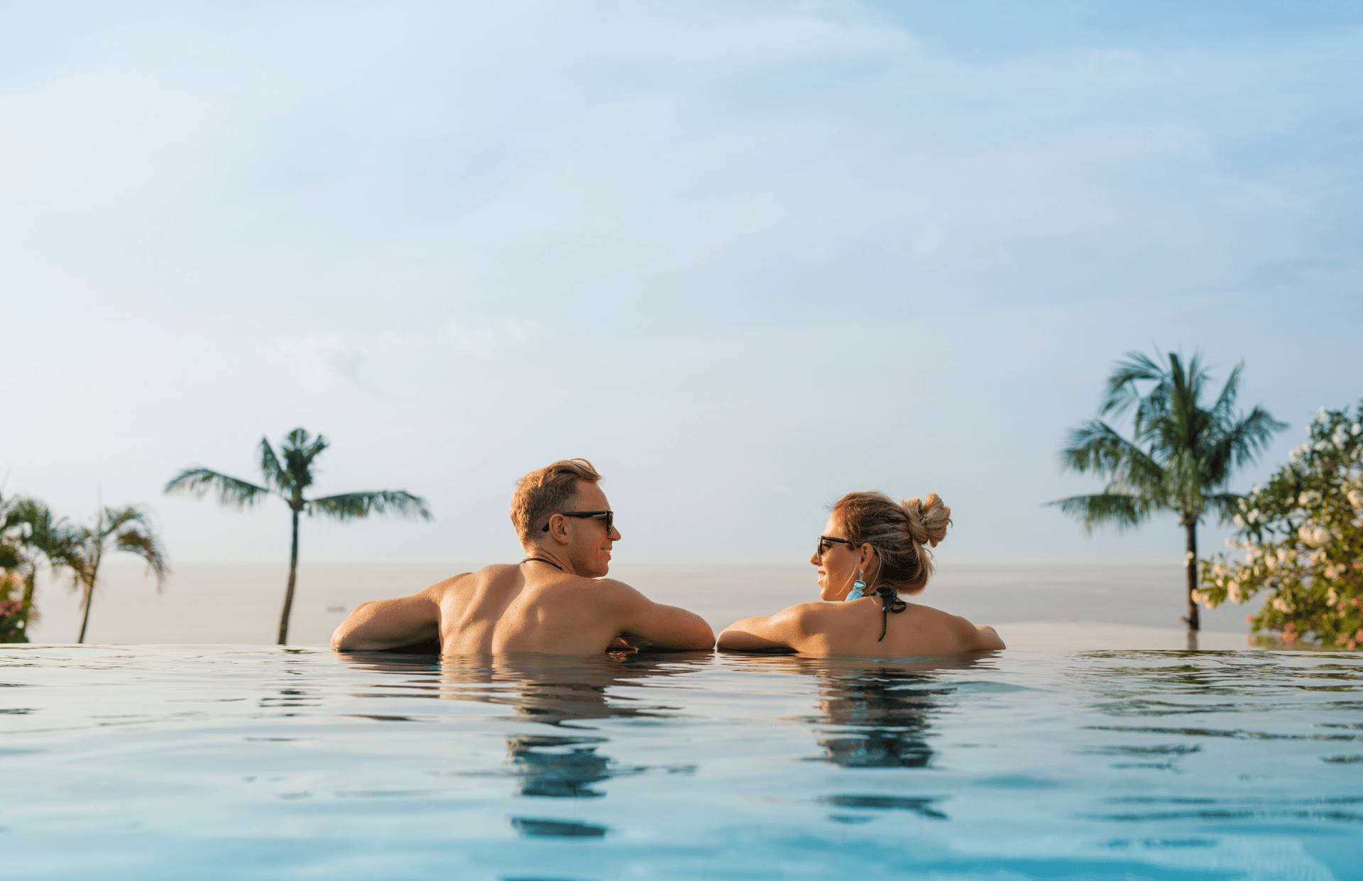 two woman leaning on inground pool tile