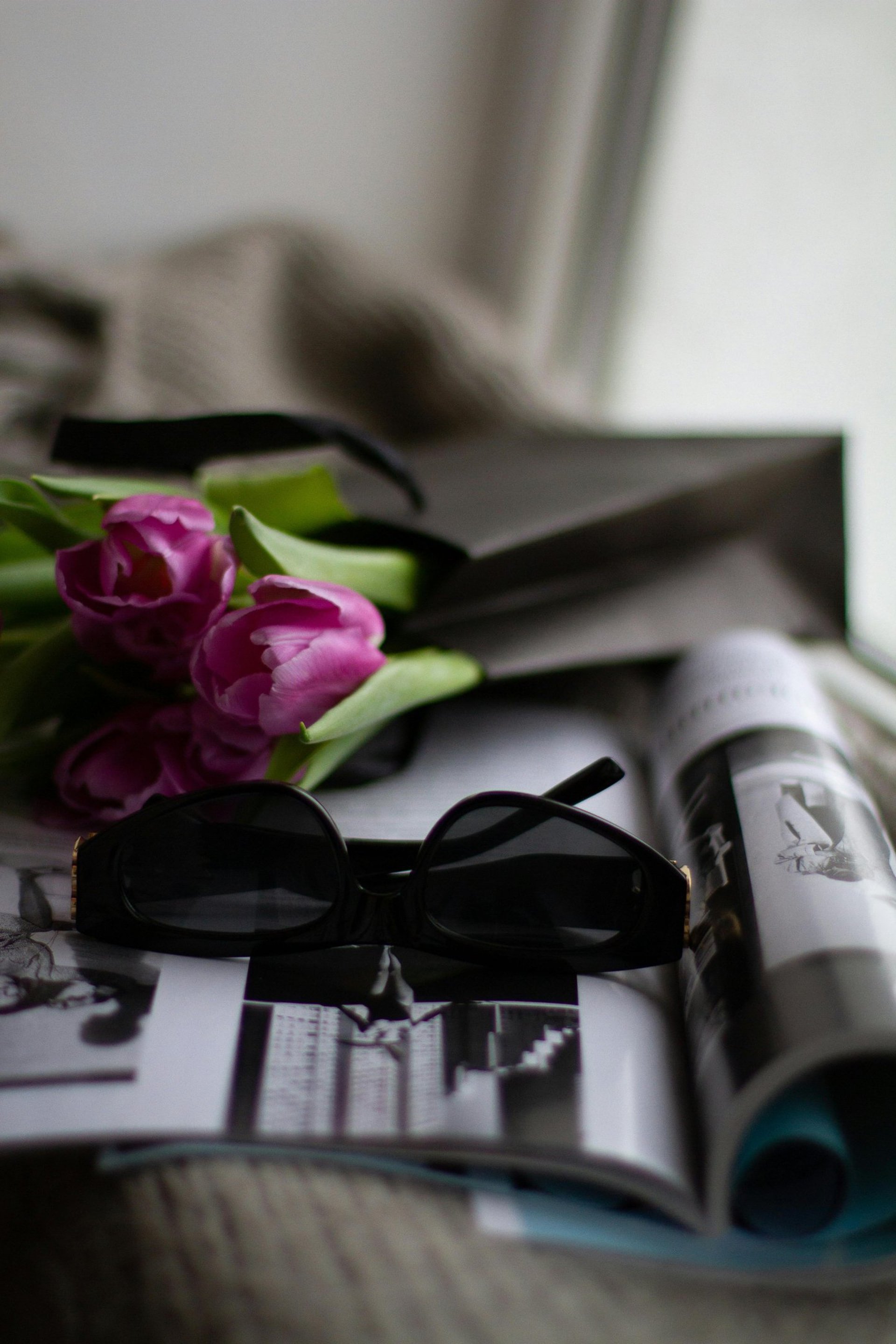 gray leather handbag beside eyeglasses and books