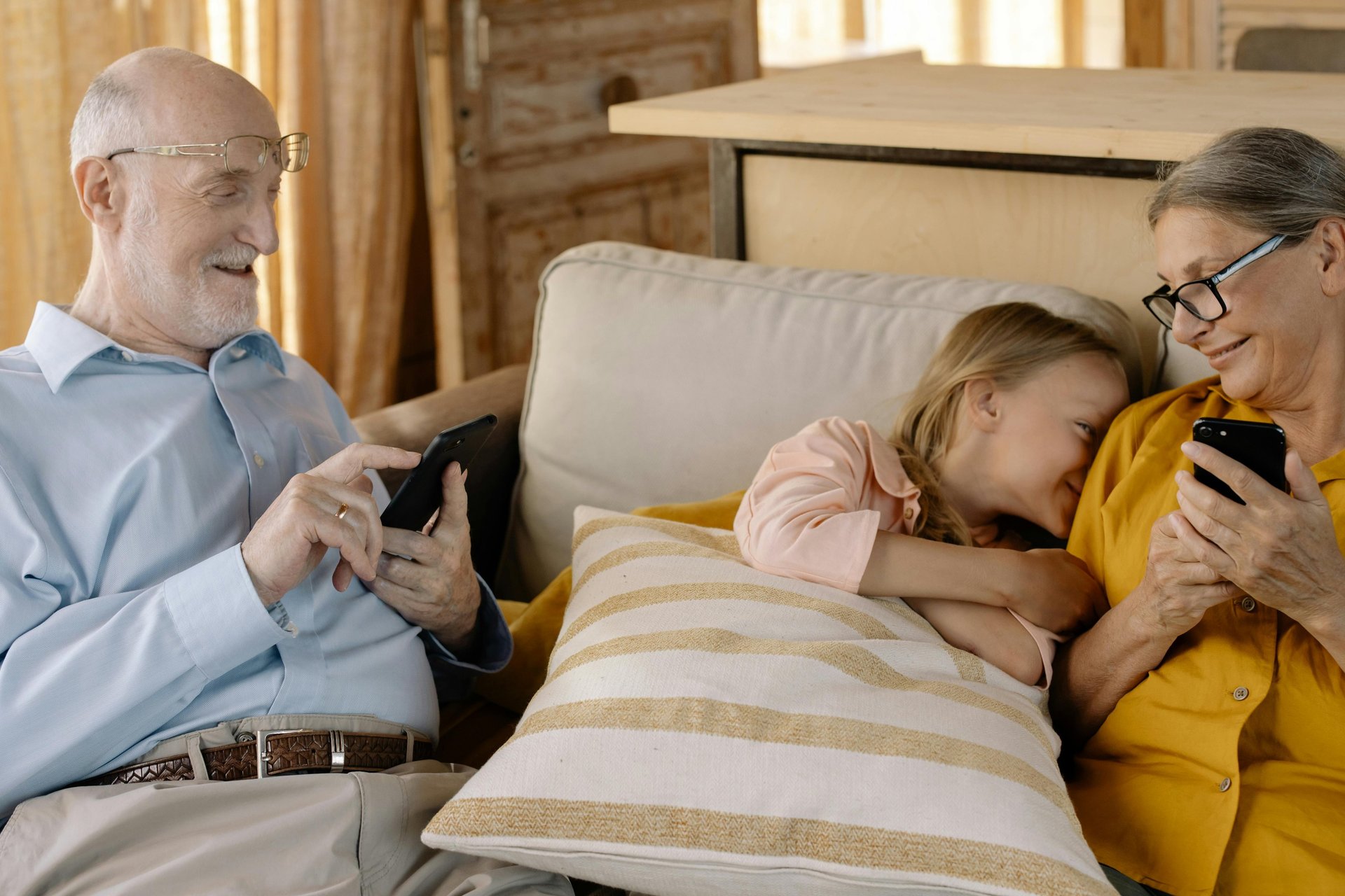 two babies and woman sitting on sofa while holding baby and watching on tablet