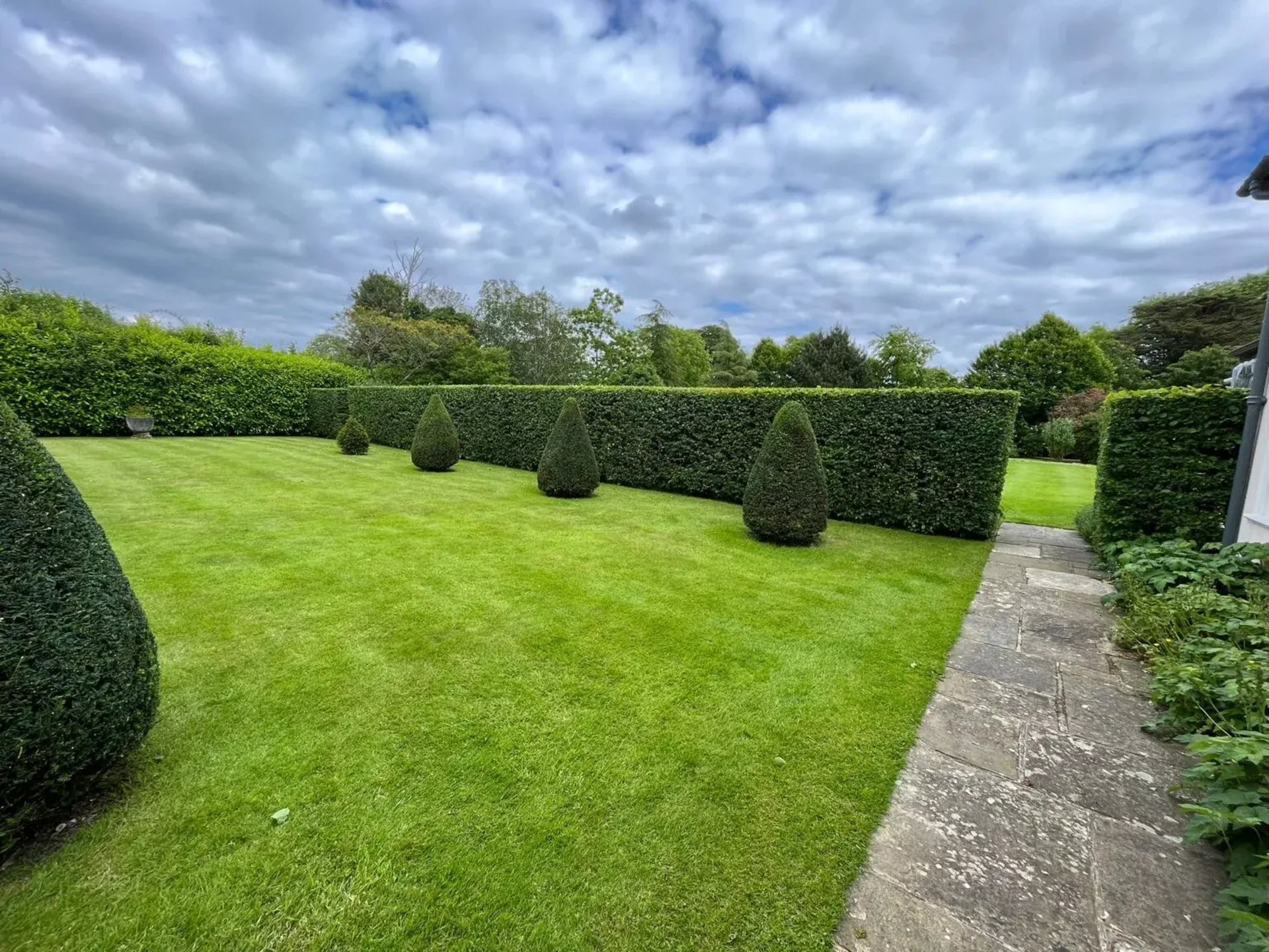 Stone pathway through a manicured garden with trees.