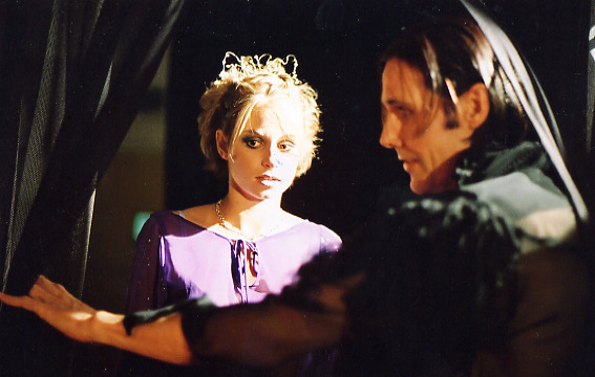 A beautiful young woman is led into a room by a sinister looking man wearing black