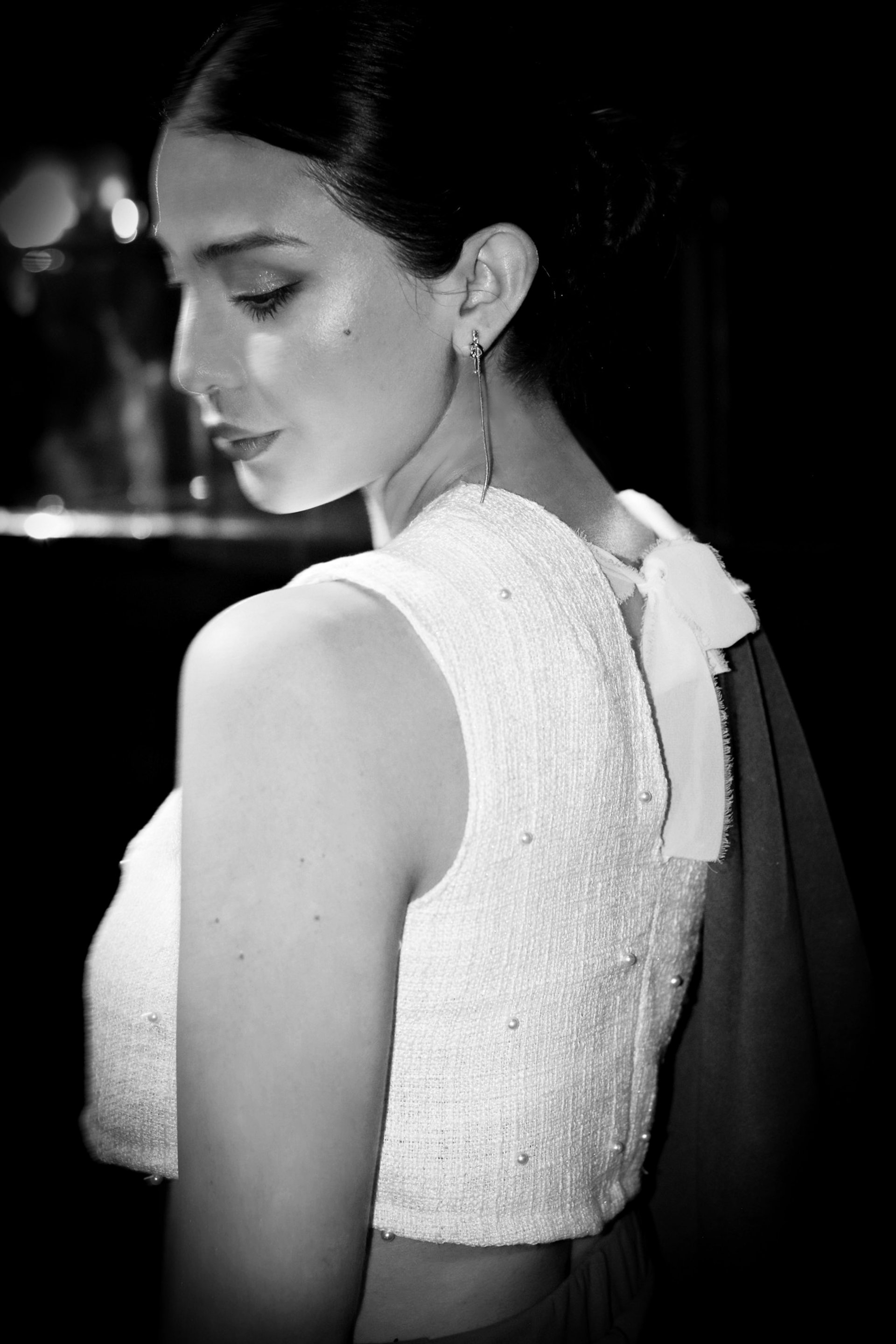 Elegant woman in a wide-brimmed hat, statement hoop earrings, and a flowing cape, captured in a black and white profile again