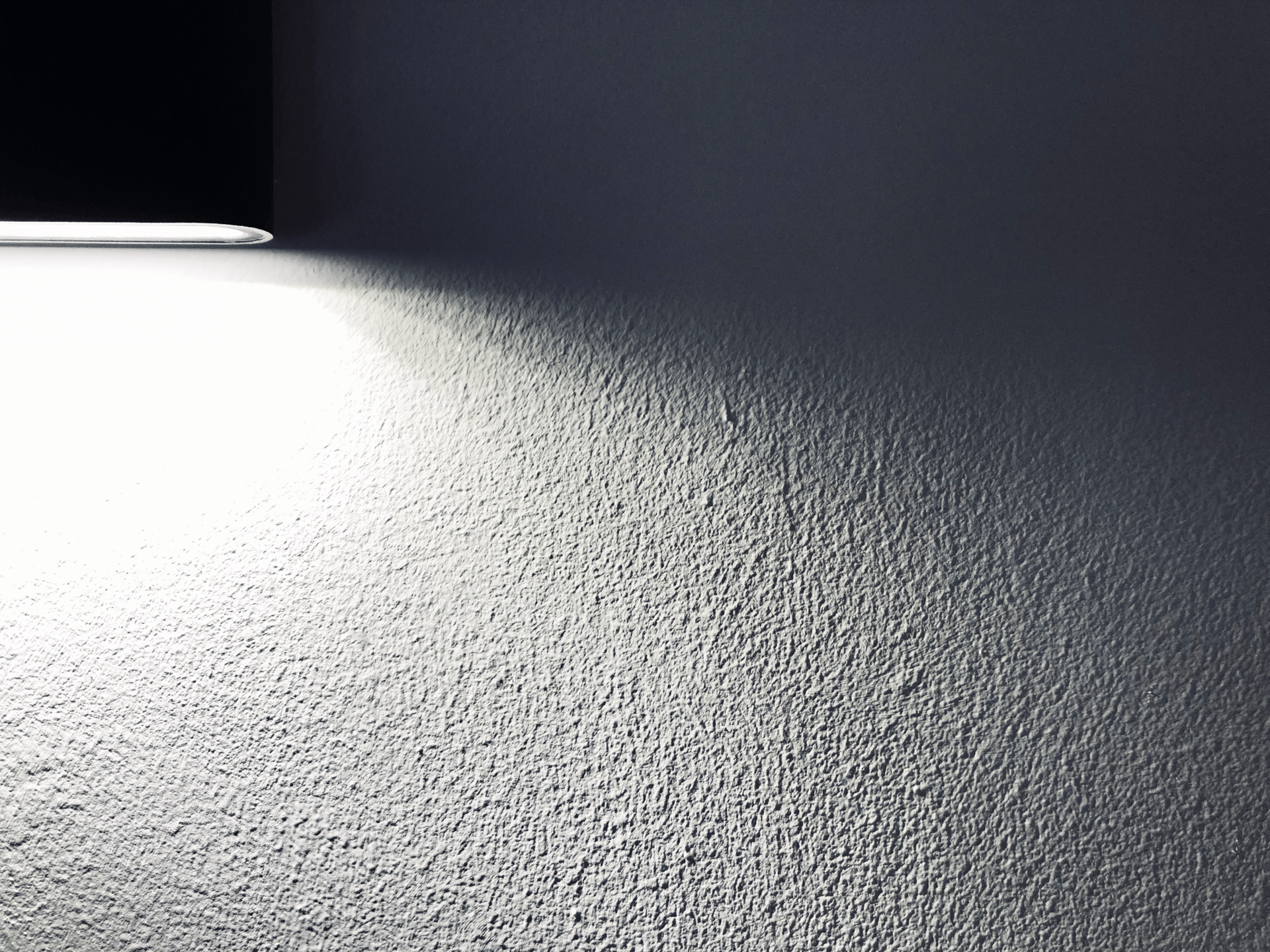 Textured home interior wall lit by spotlight, suitable for illustrating hidden damages assessed during insurance claims.