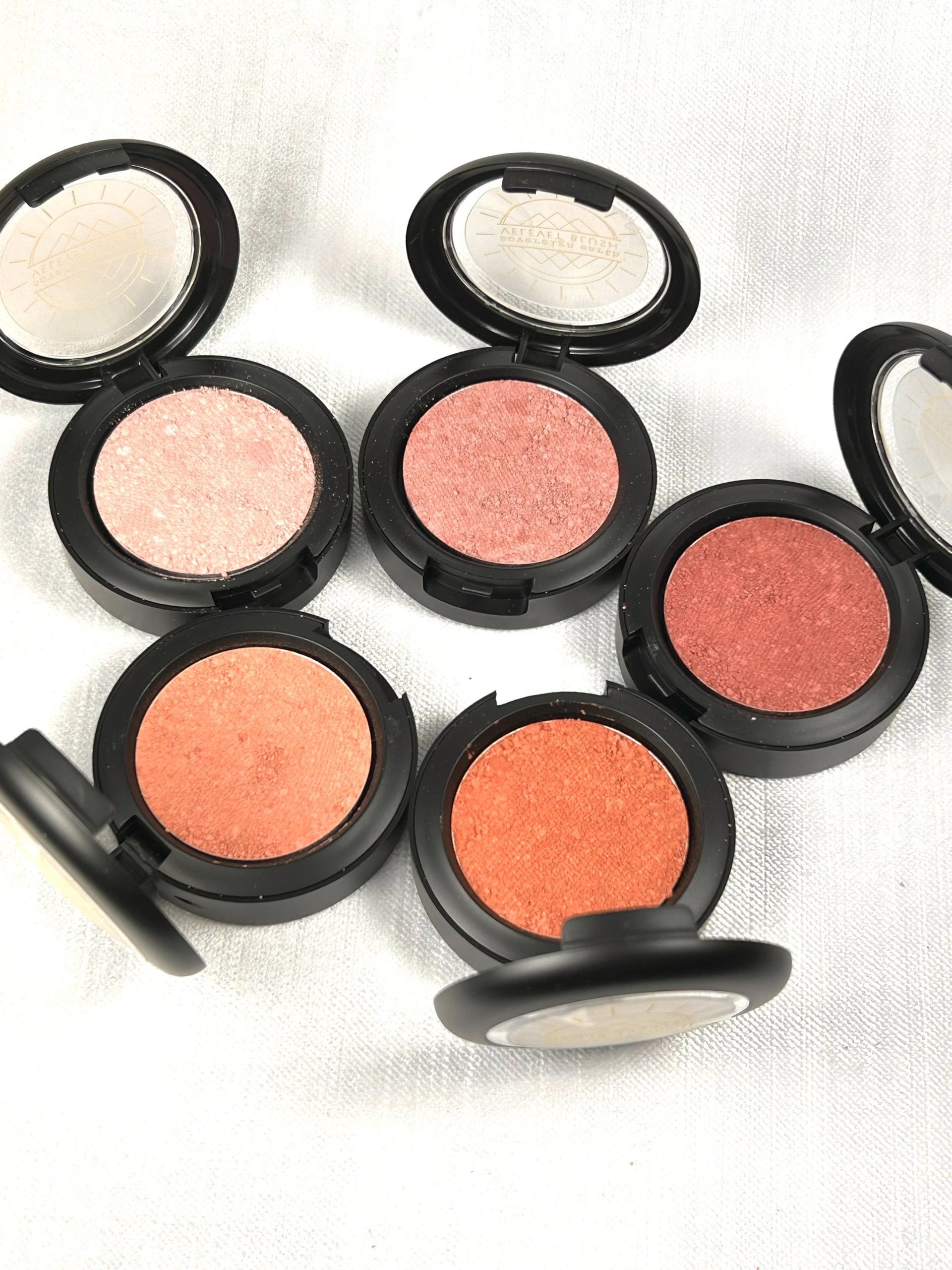 three makeup brushes on top of compact powders