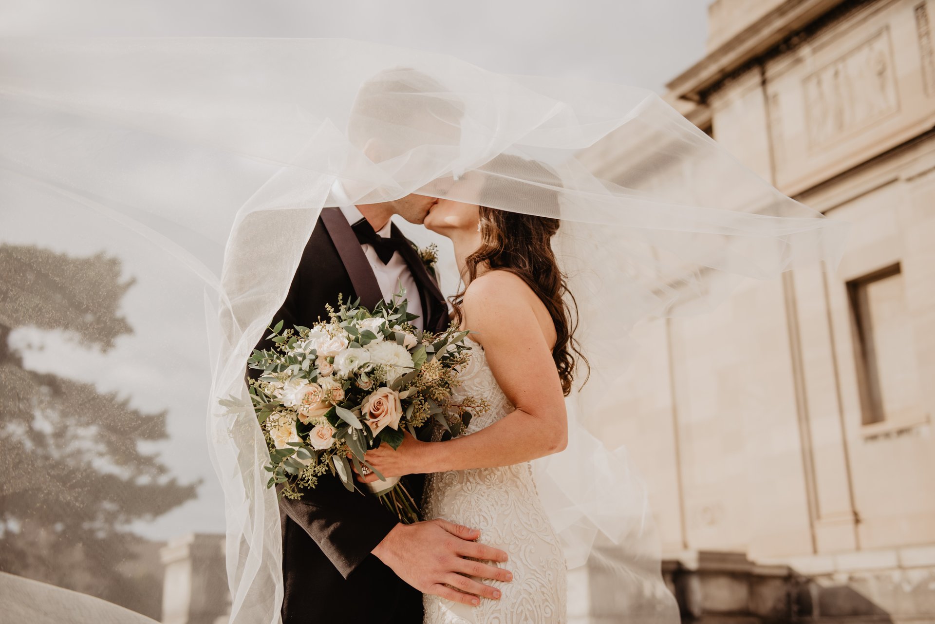woman in white wedding dress stands in front of man in tuxedo
