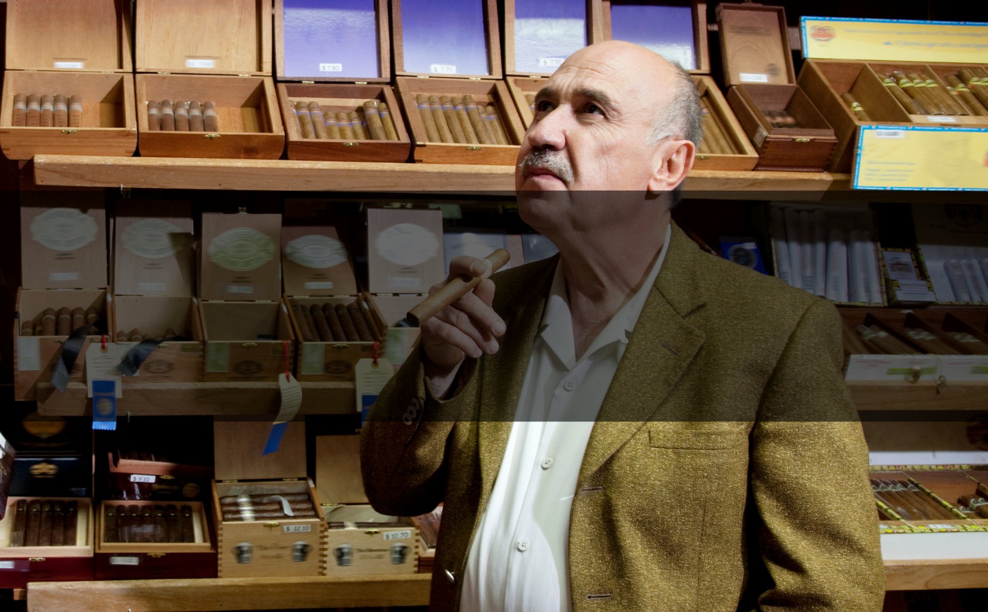 Un homme debout en costume et cravate avec à la main un cigare avec bandeau noir