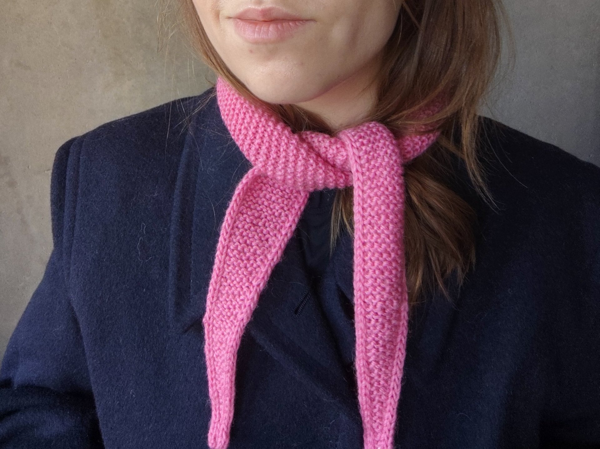 różowy wełniany szalik na szyi kobiety ubranej w granatowy płaszcz