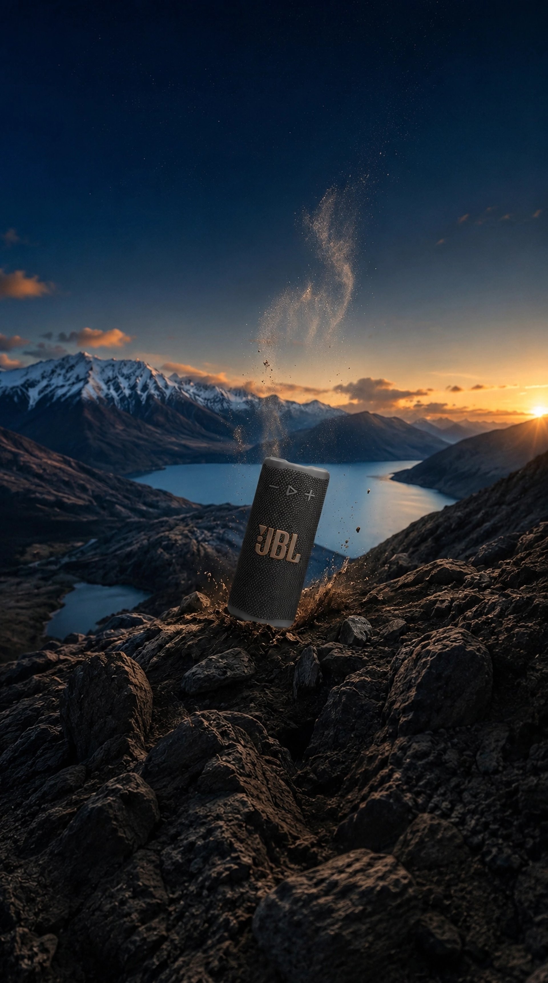 JBL GRIP sur paysage montagneux au coucher du soleil avec effet de projection de terre et pierres.