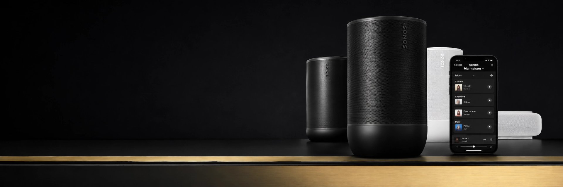 Enceintes Sonos Move 2 noire et blanche avec smartphone sur un meuble au liseré doré, fond noir minimaliste.