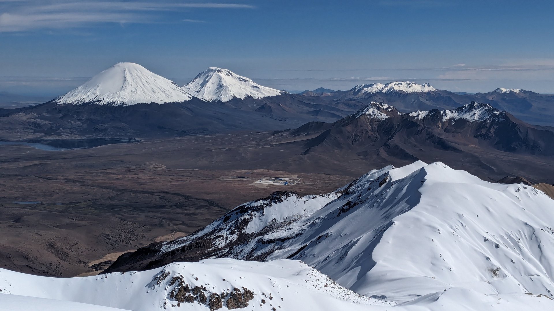 a couple sits on a rock looking out over a lake