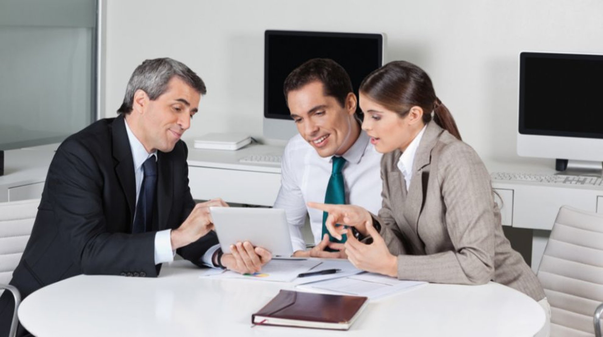 two people shaking hands in front of a laptop