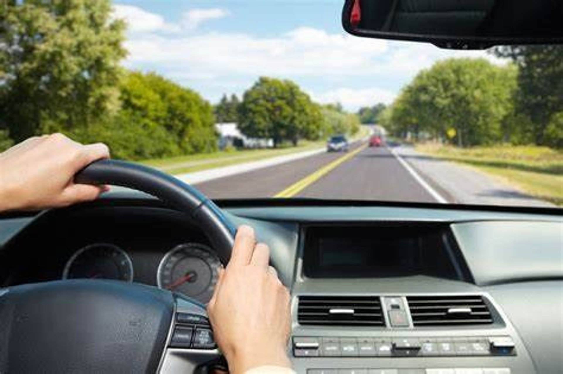a man driving a car with his hand on the steering wheel