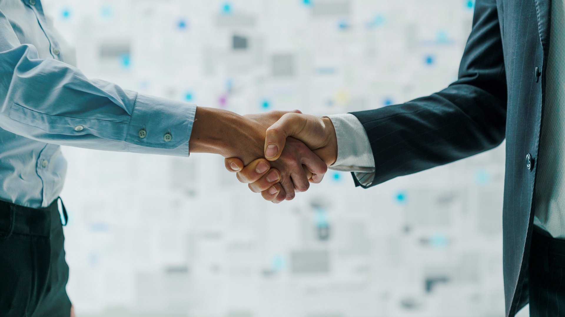 two people shaking hands over a wooden table