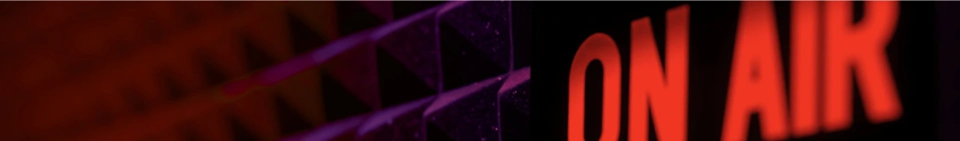 On Air sign glowing red inside Miami podcast studio with black and red acoustic background.