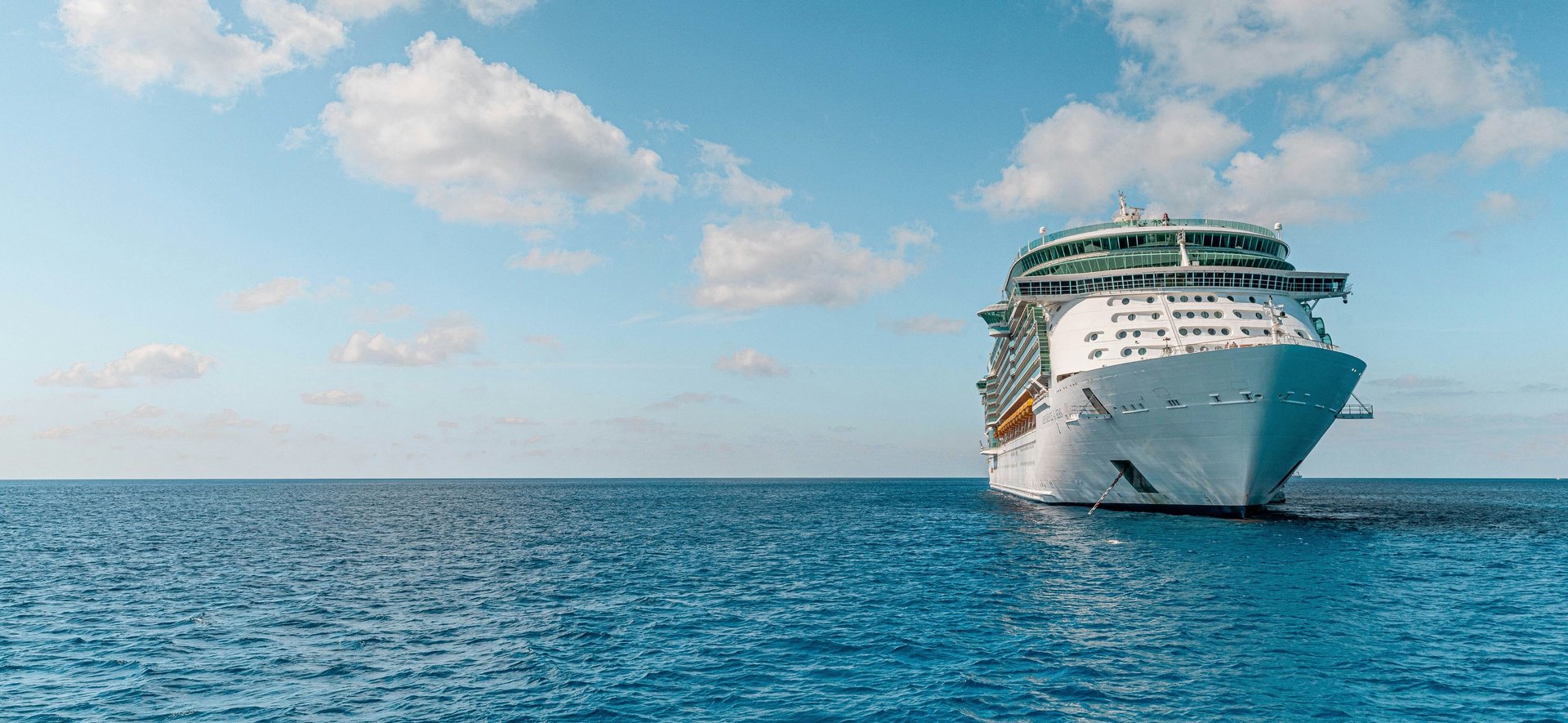 white and blue ship on sea under blue sky and white clouds during daytime