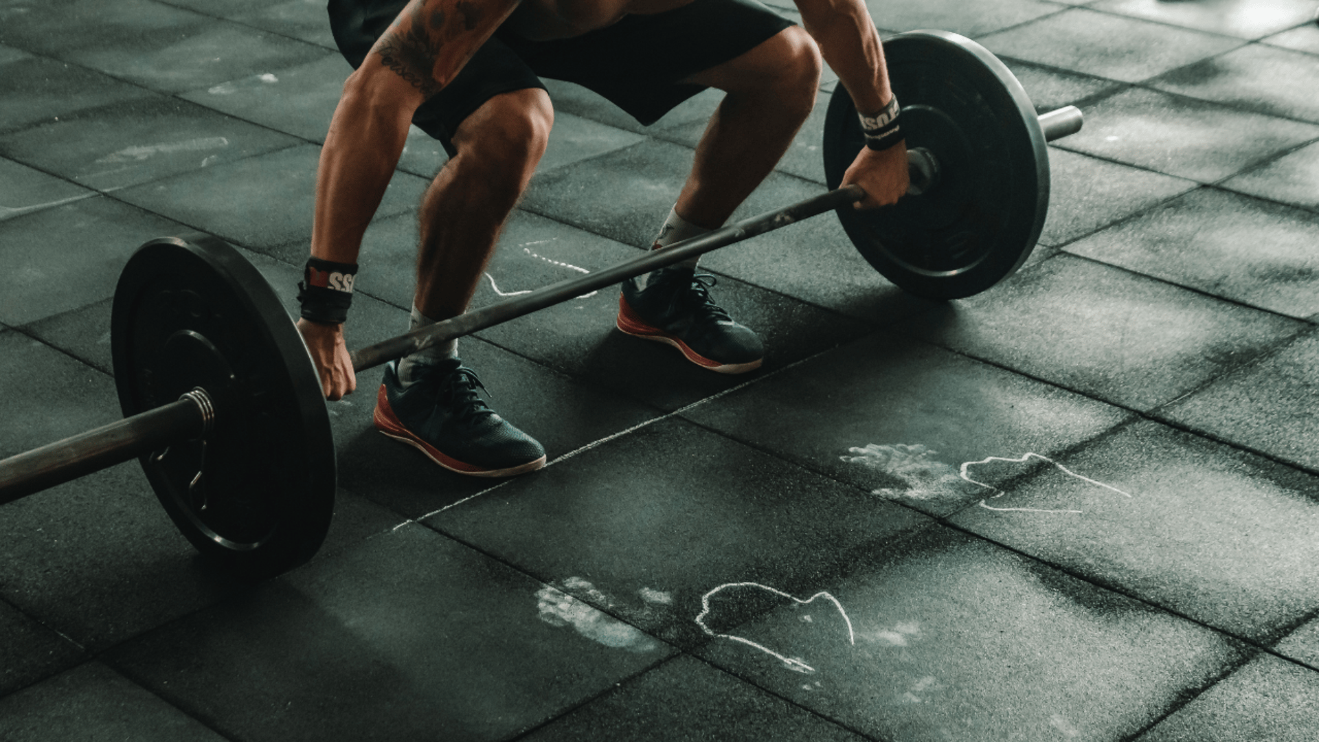 topless man in black shorts sitting on black and silver barbell