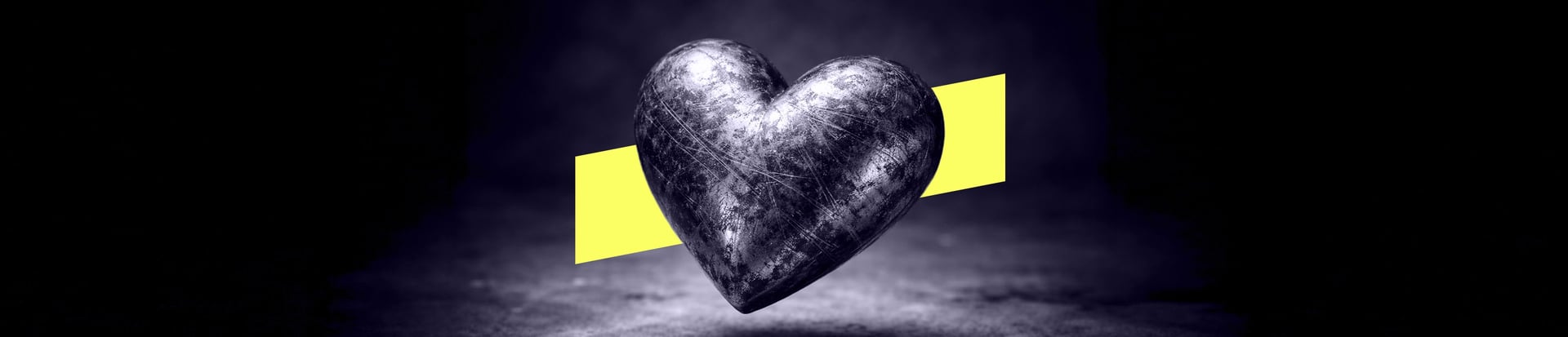 A scratched, dented heart made of steel against a dark background.