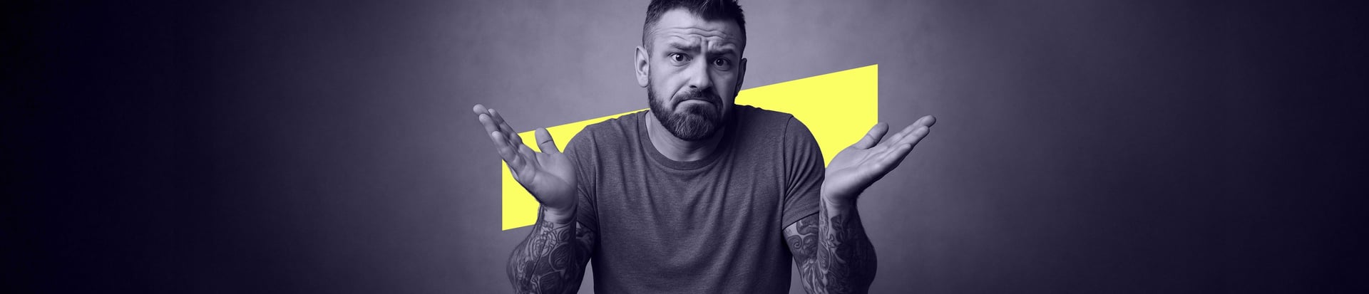 A man with tattoos on both arms shrugs with raised eyebrows, palms up, and a yellow shape behind him.
