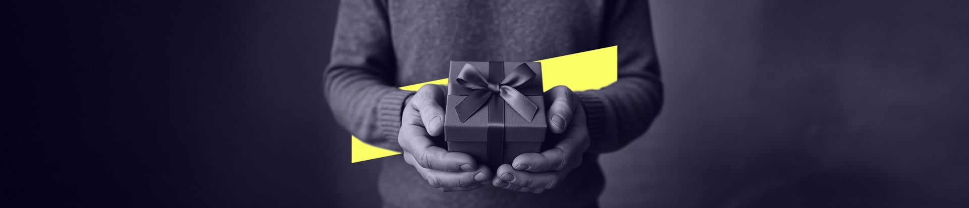 A pair of hands holds out a neatly wrapped gift box with a ribbon against a yellow background shape.