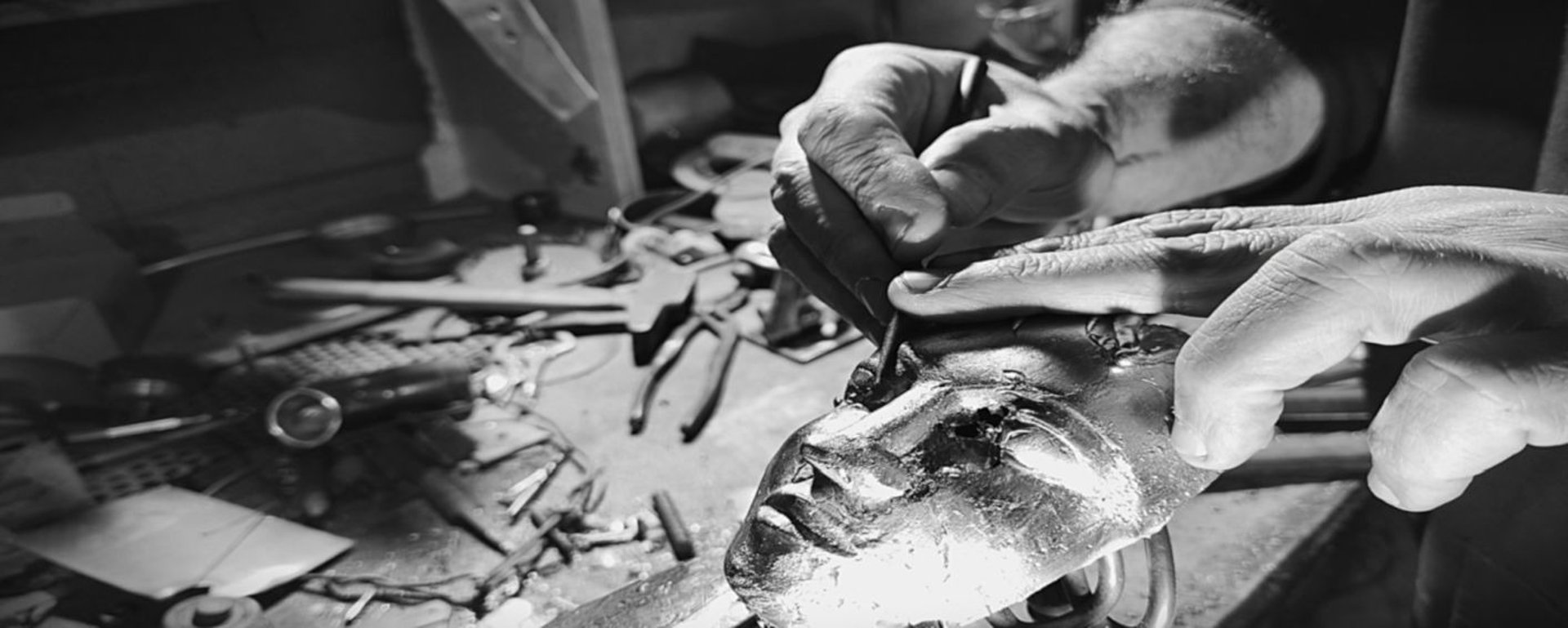 detail de mains d'artisan au travail de ciselure d'un bronze MikaCréations