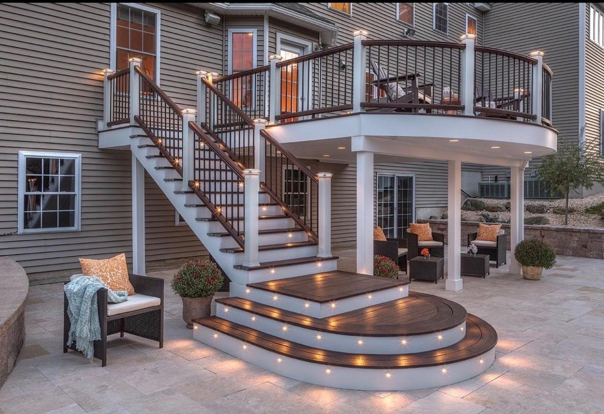 a deck with chairs and tables on it next to a house